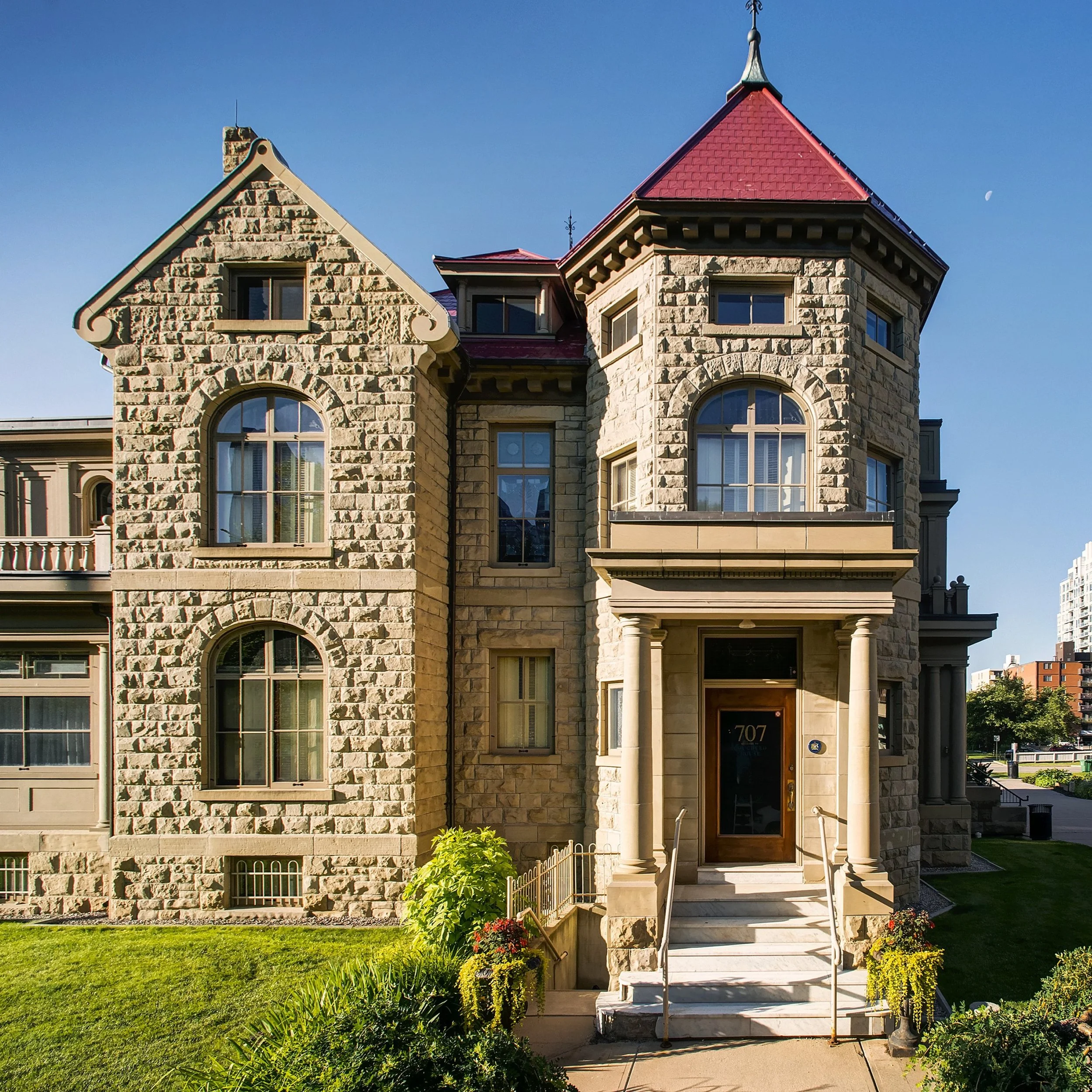 Image of the front of Lougheed House. The sky is blue.