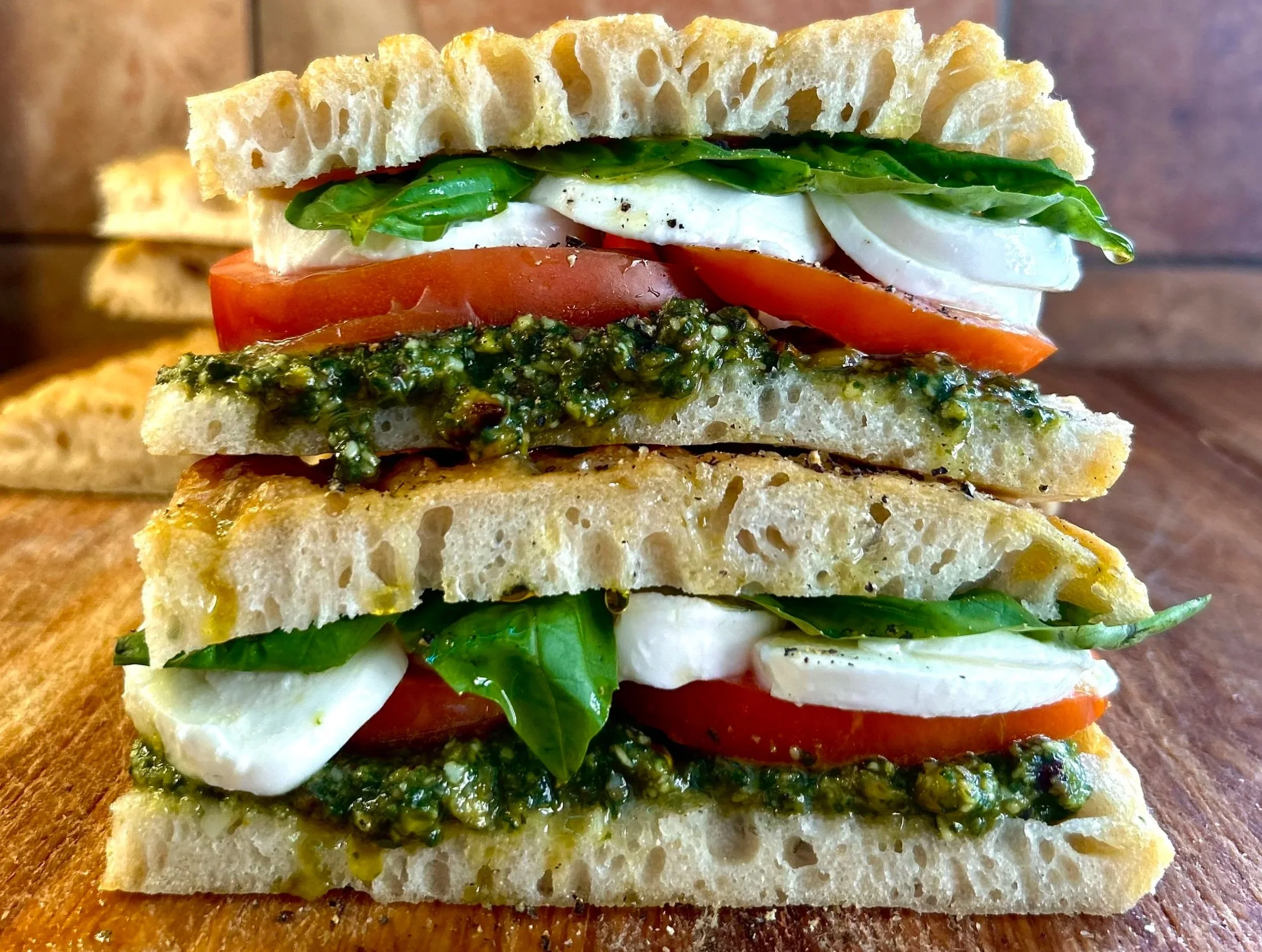 LUNCH Sandwich Shop fresh, authentic Italian sandwich with pieces of fresh basil, tomato, fresh mozzarella cheese, and pistachio basil pesto spread on fresh baked Italian schiacciata bread.