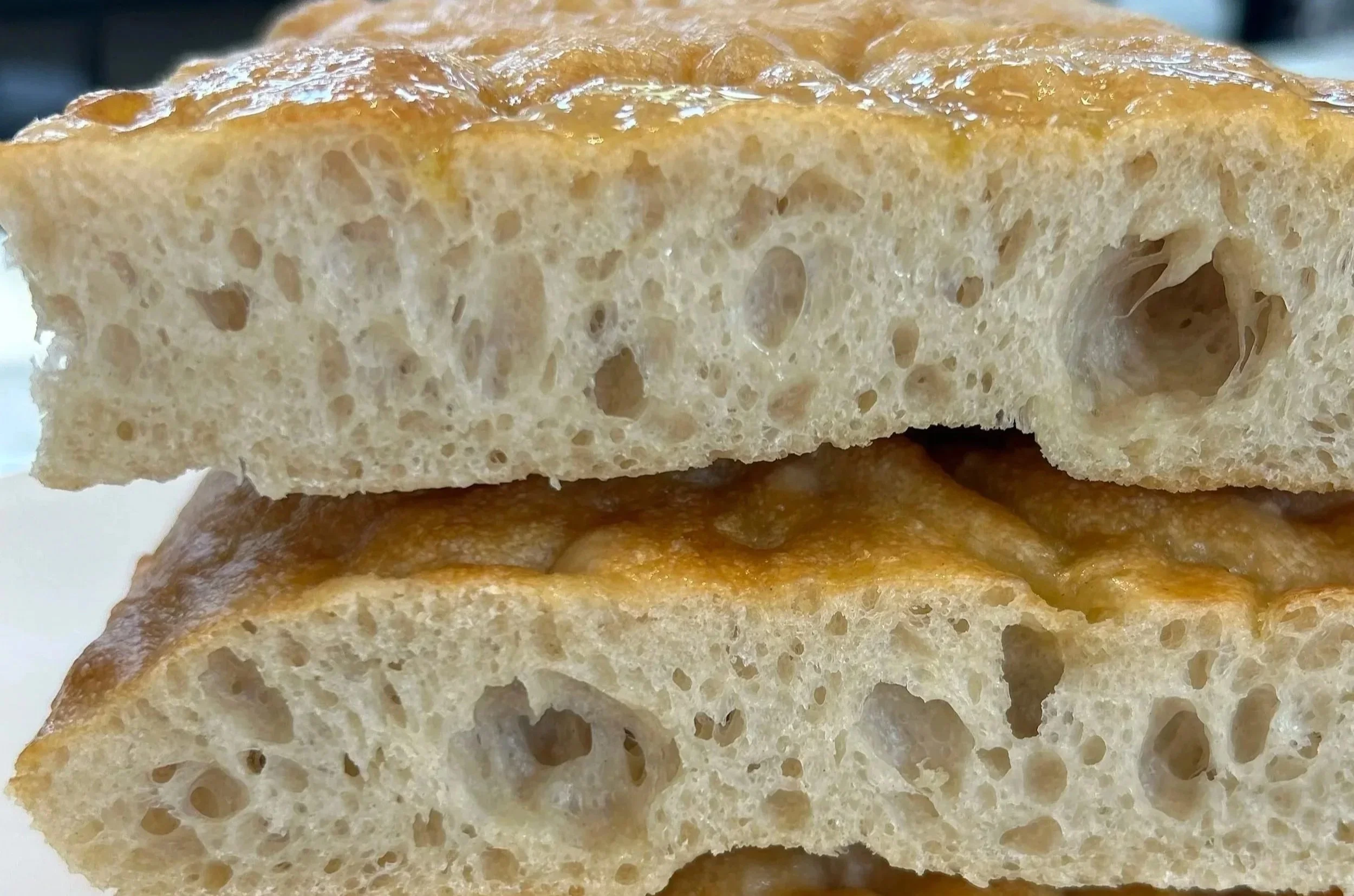 Close-up of a toasted bread slice showing its airy, bubbly interior and crispy crust.