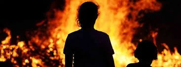 Silouette of a child watching a building burn