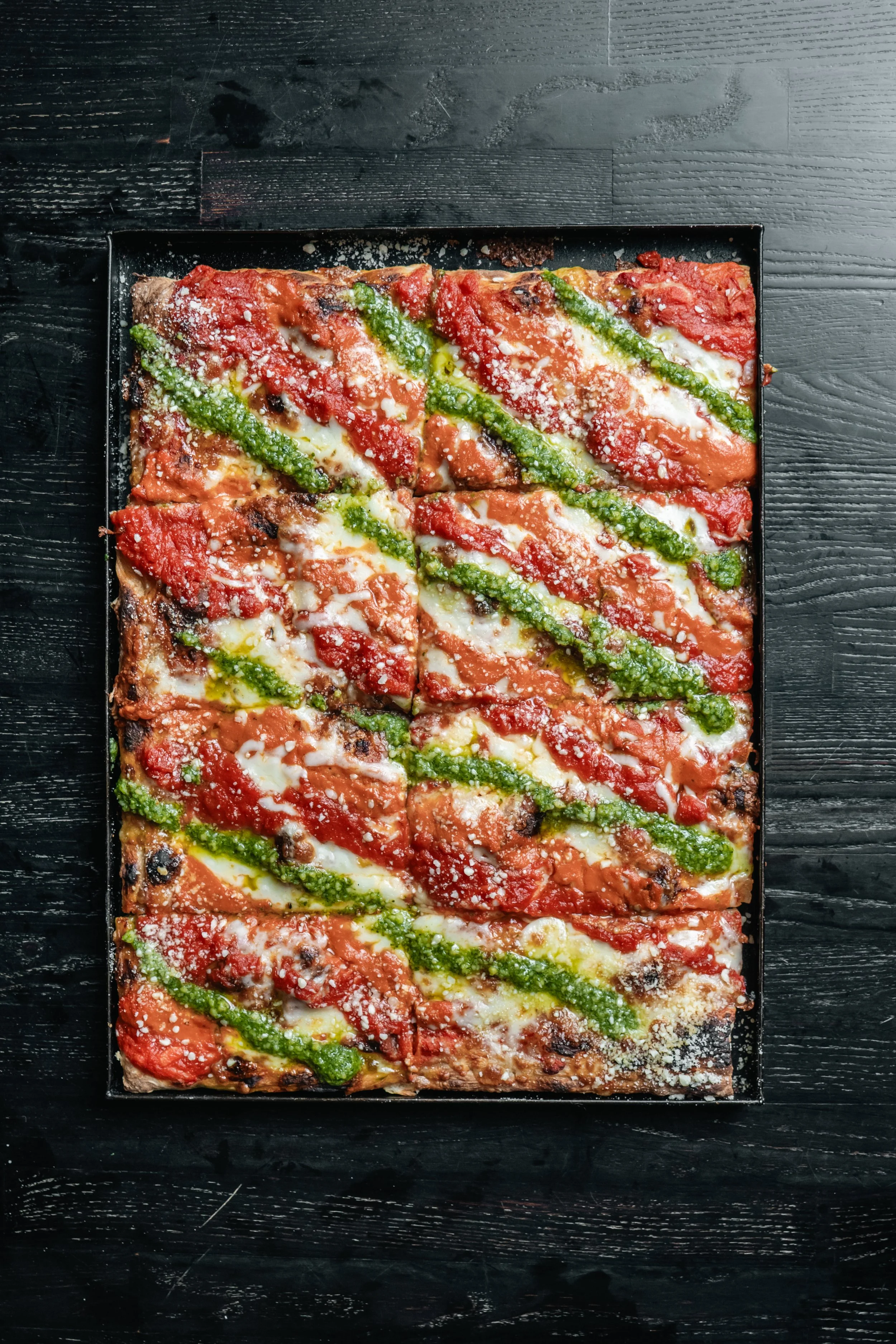 The Trio Roman-style pizza with tomato sauce, vodka sauce, and green pesto in diagonal stripes.