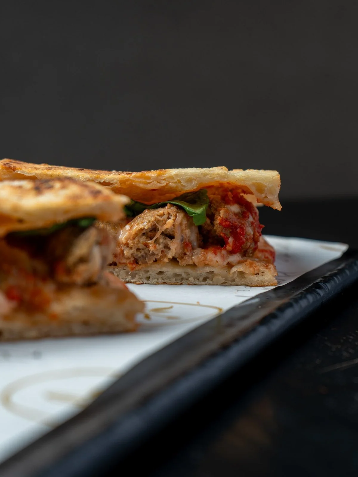 Meatball panini with tomato sauce and melted cheese, cut in half on a serving tray.