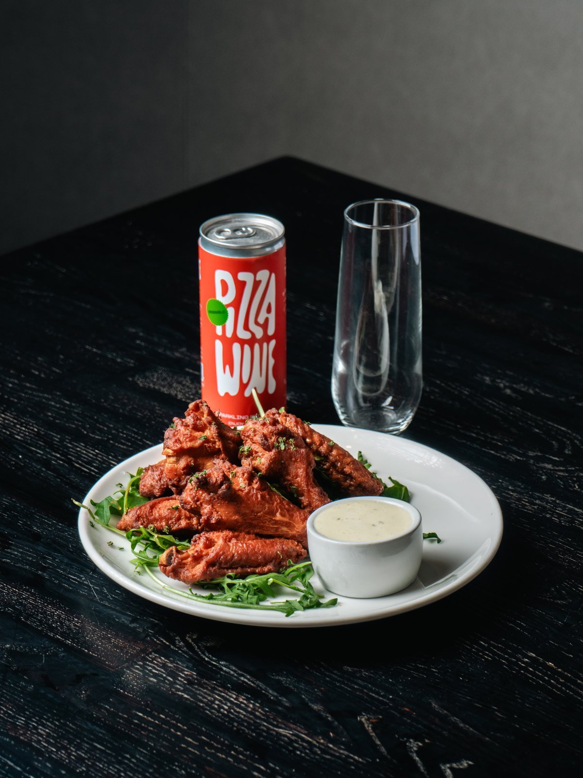 Pizza Wine can and a glass beside a plate of wings