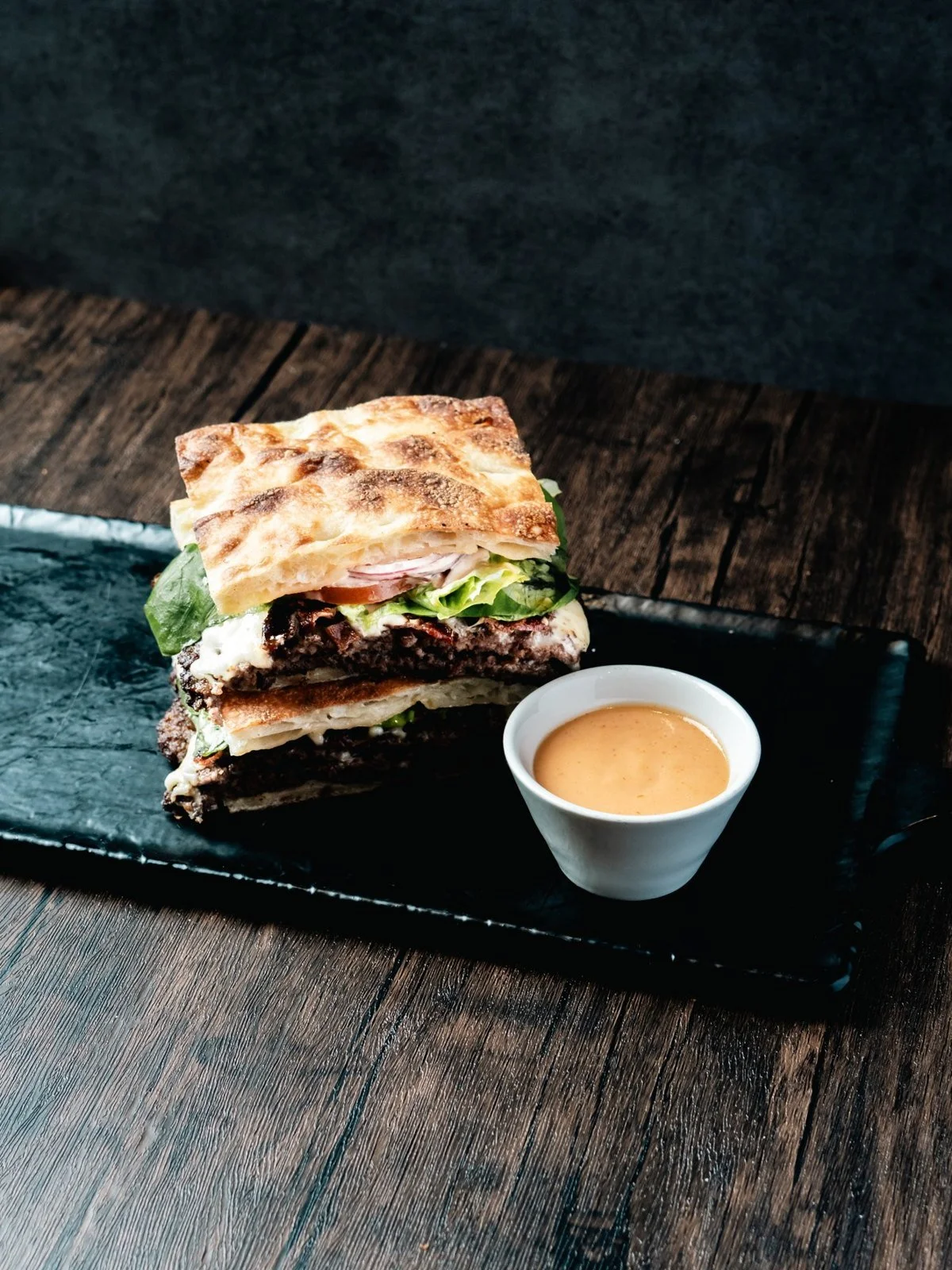 Florenza smashburger on panini bread, served with a cup of dipping sauce.