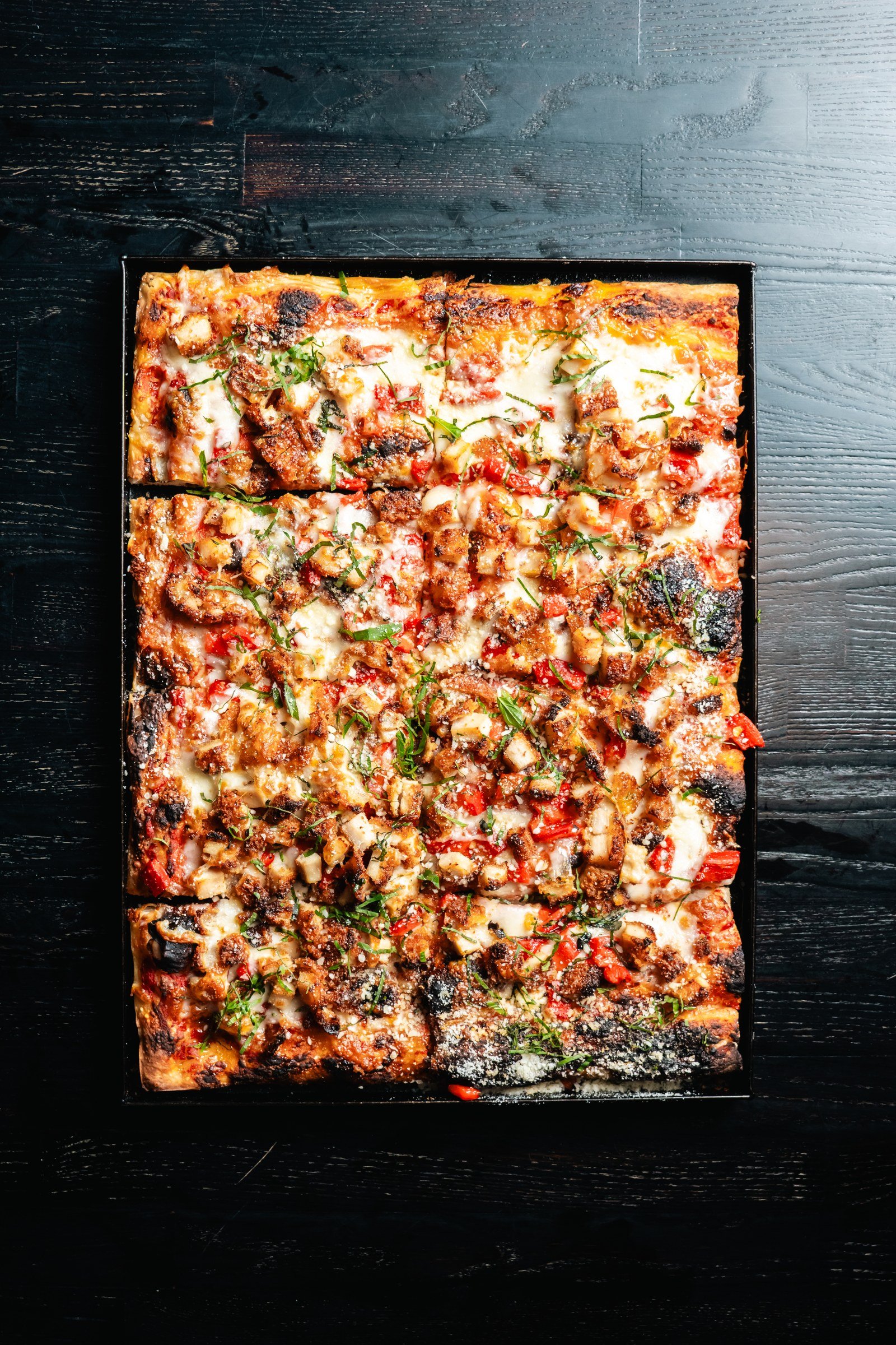 Milanesa Roman-style pizza with chicken cutlet and roasted red pepper, photographed overhead.