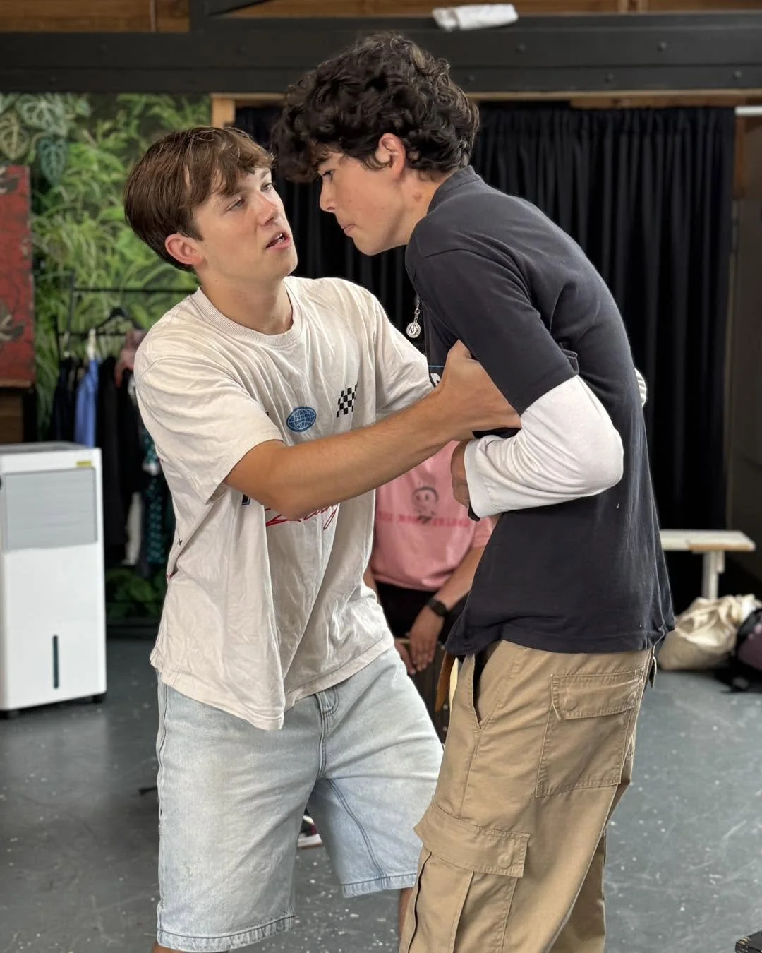 Two young men are in a heated argument or confrontation, with one grabbing the other by the shirt.