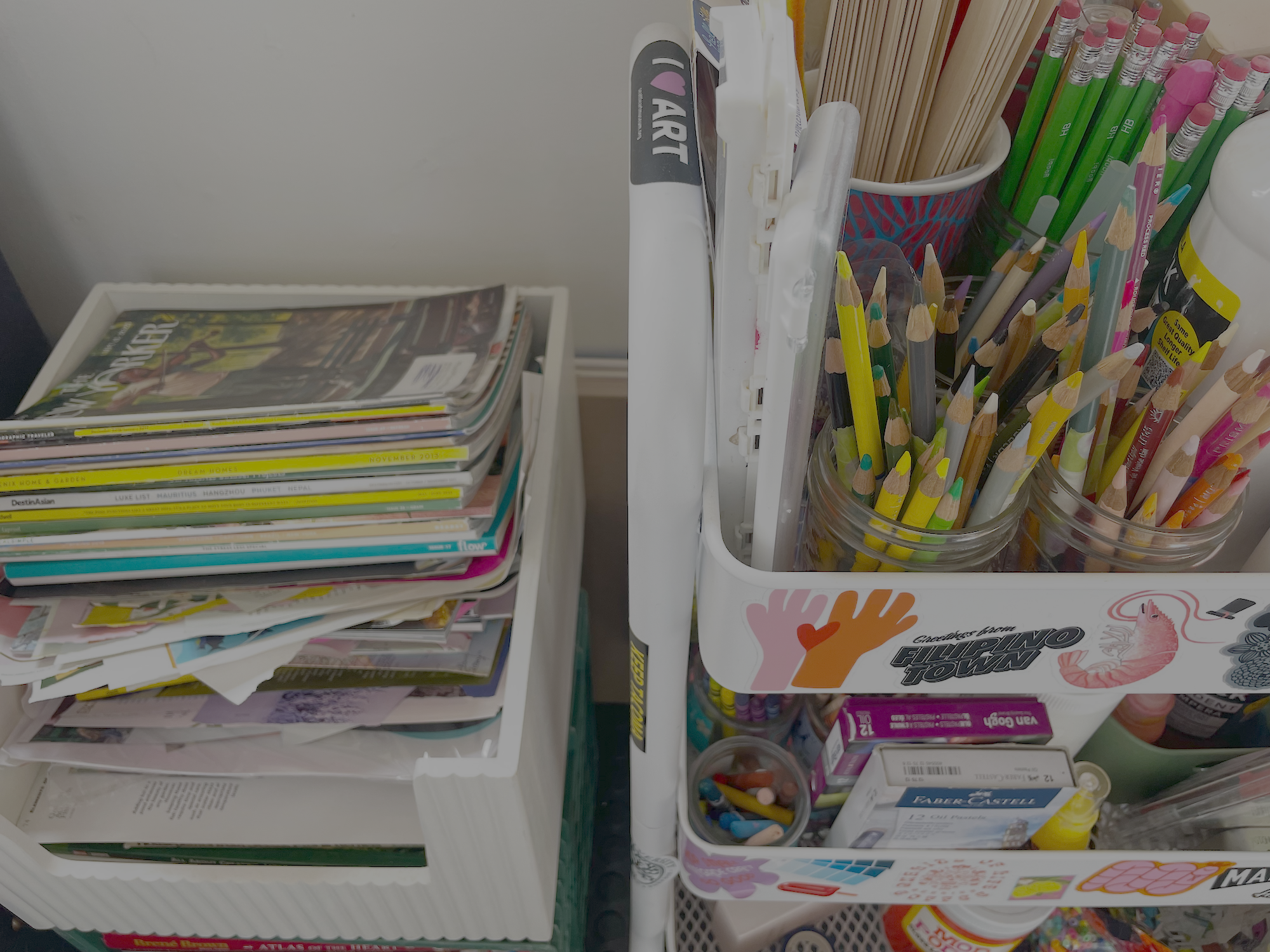 A shelf with various colored pencils, a stack of magazines, and stationery items such as glue and markers.