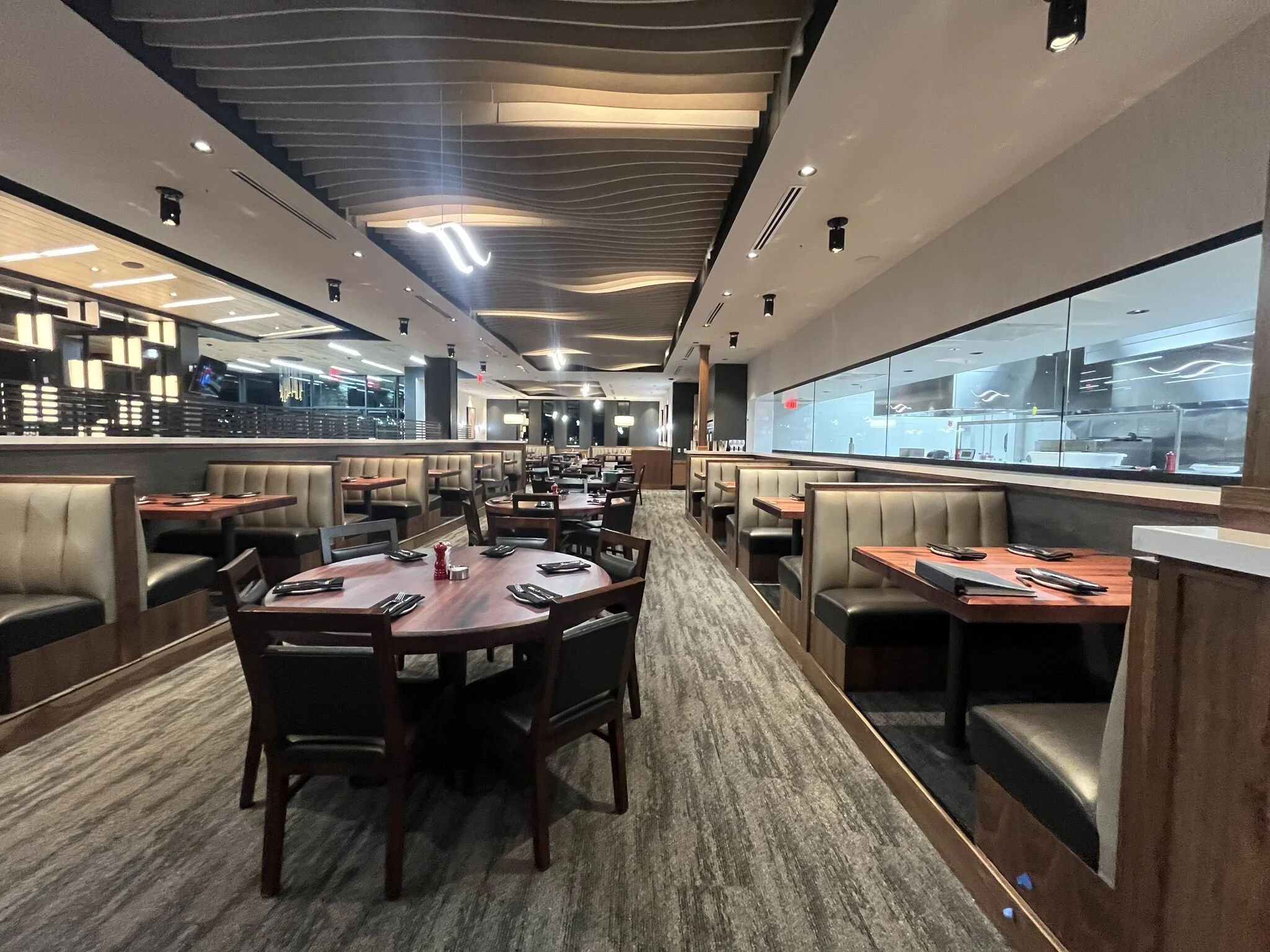Interior view of dining area tables, chairs, booths, cool wave panel ceiling. Great bar on the left side #stoneyriver