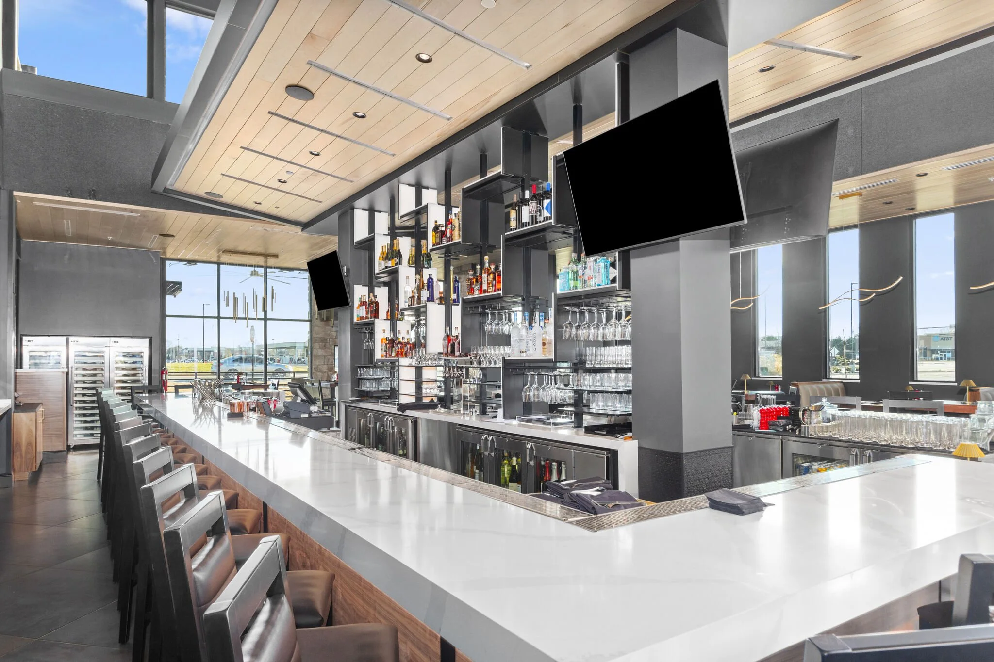 Interior view of bar area showcasing a lot of natural light and bar stools, with cool wood panel ceiling. #stoneyriver