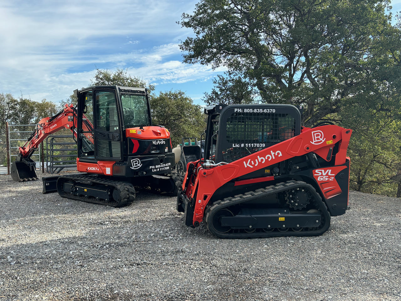 Two Kubota vehicles on a gravel surface.