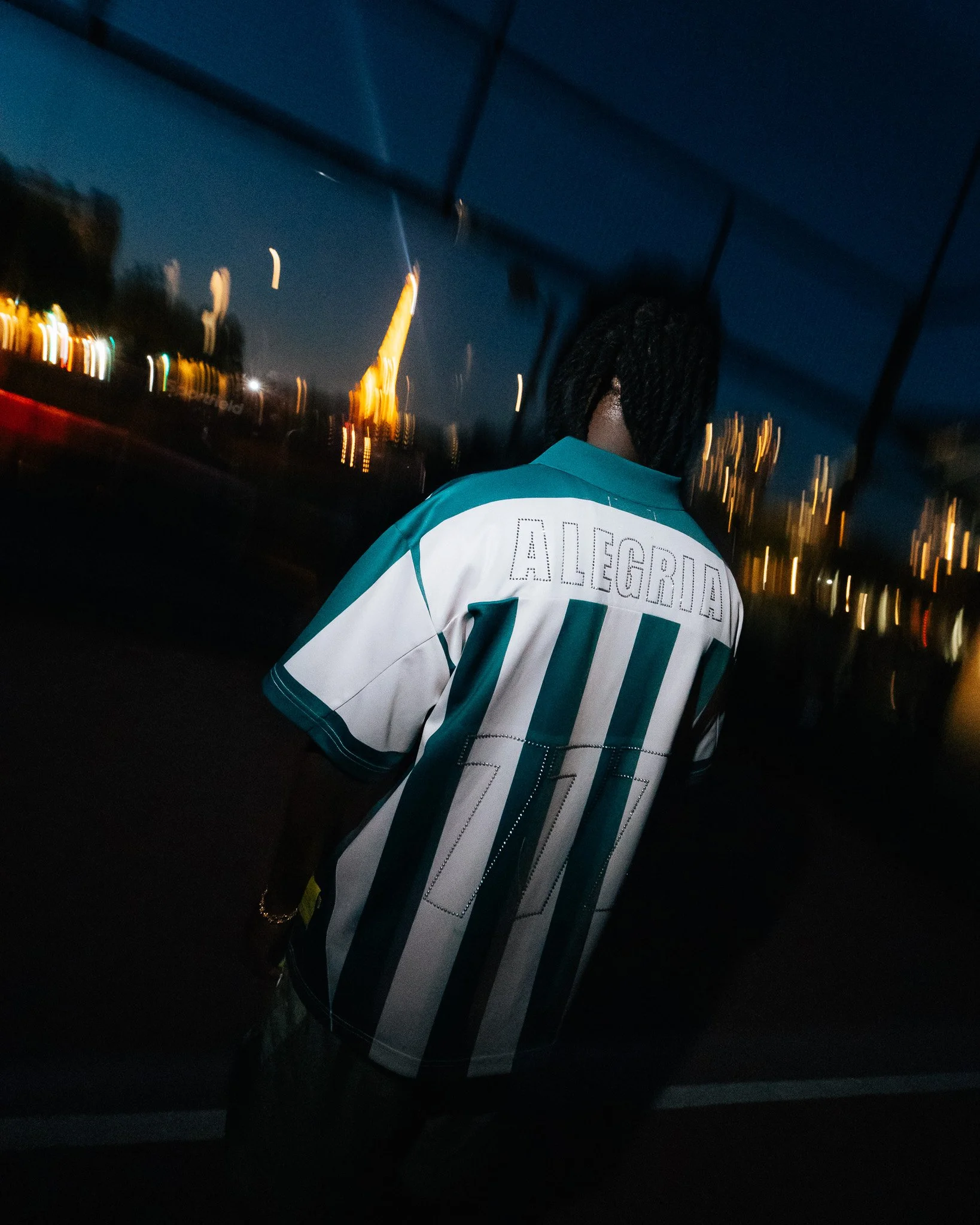 Une personne portant un maillot de football à rayures verticales avec le nom "ALEGGRI" et le numéro "10", vue de dos, sur un terrain de padel à Paris