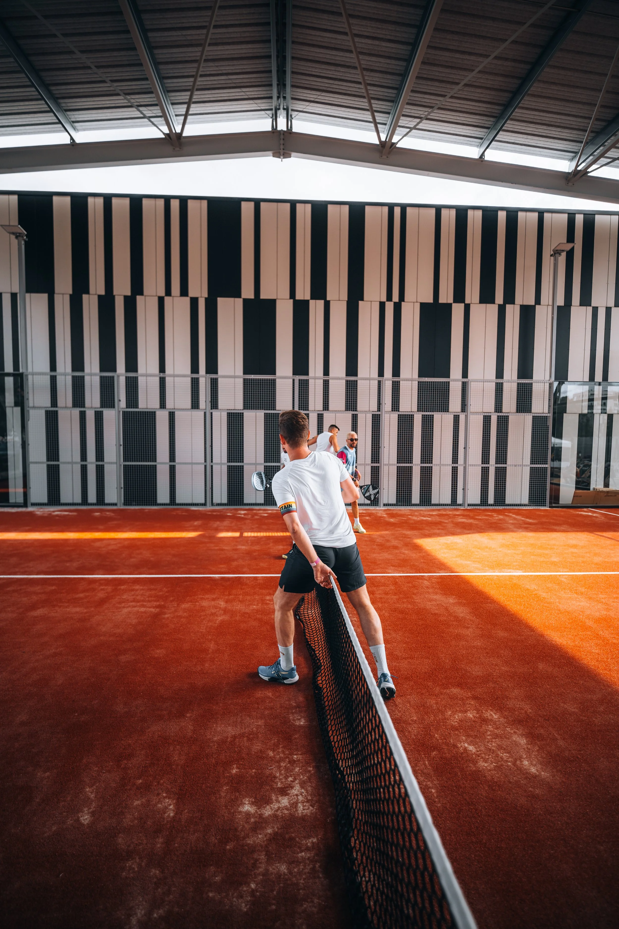 Jeu de padel à lyon avec deux hommes en action sur un court en terre battue, séparés par un filet.