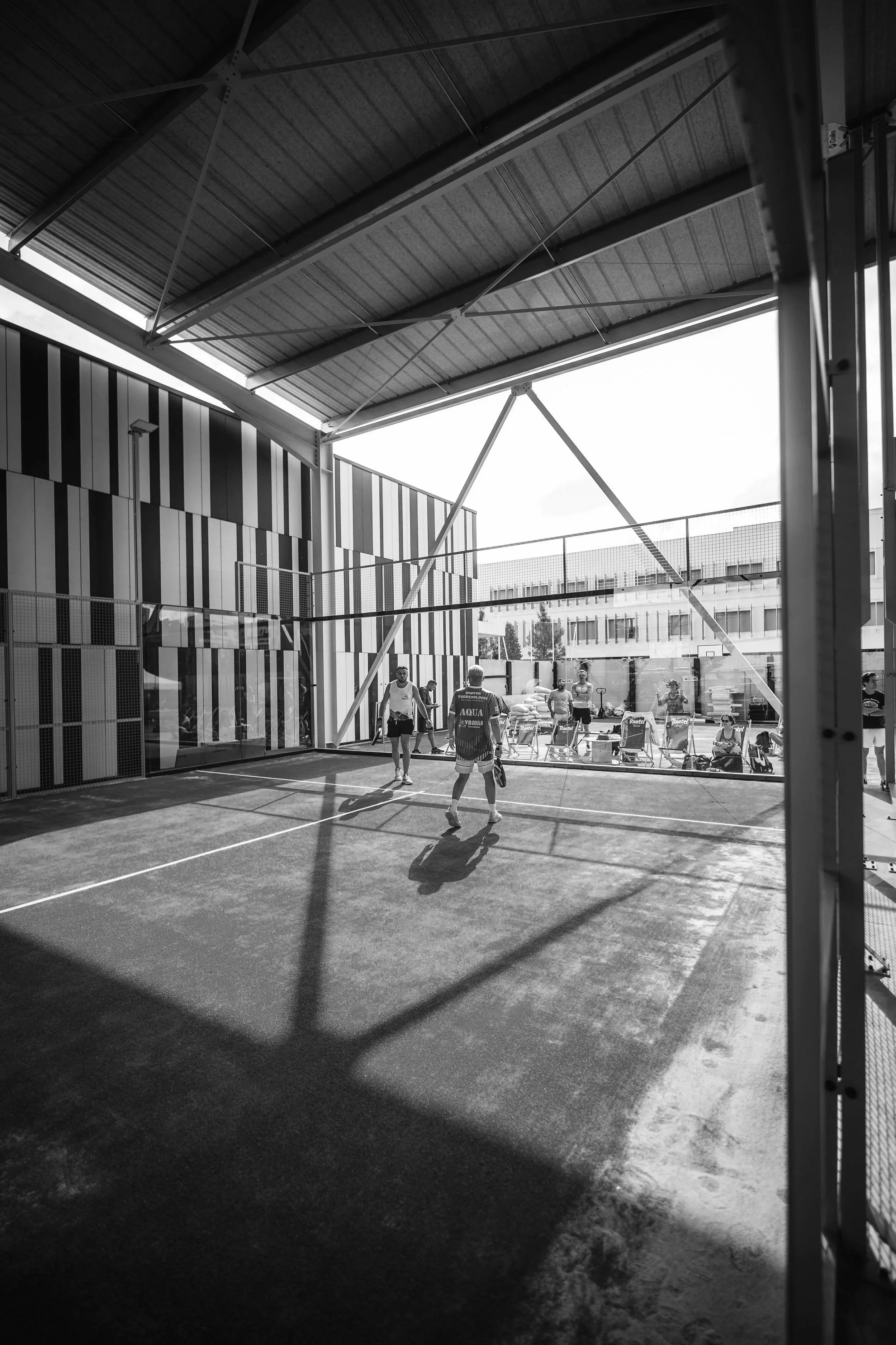 Photo en noir et blanc d'un court de padel à lyon couvert avec des joueurs en action