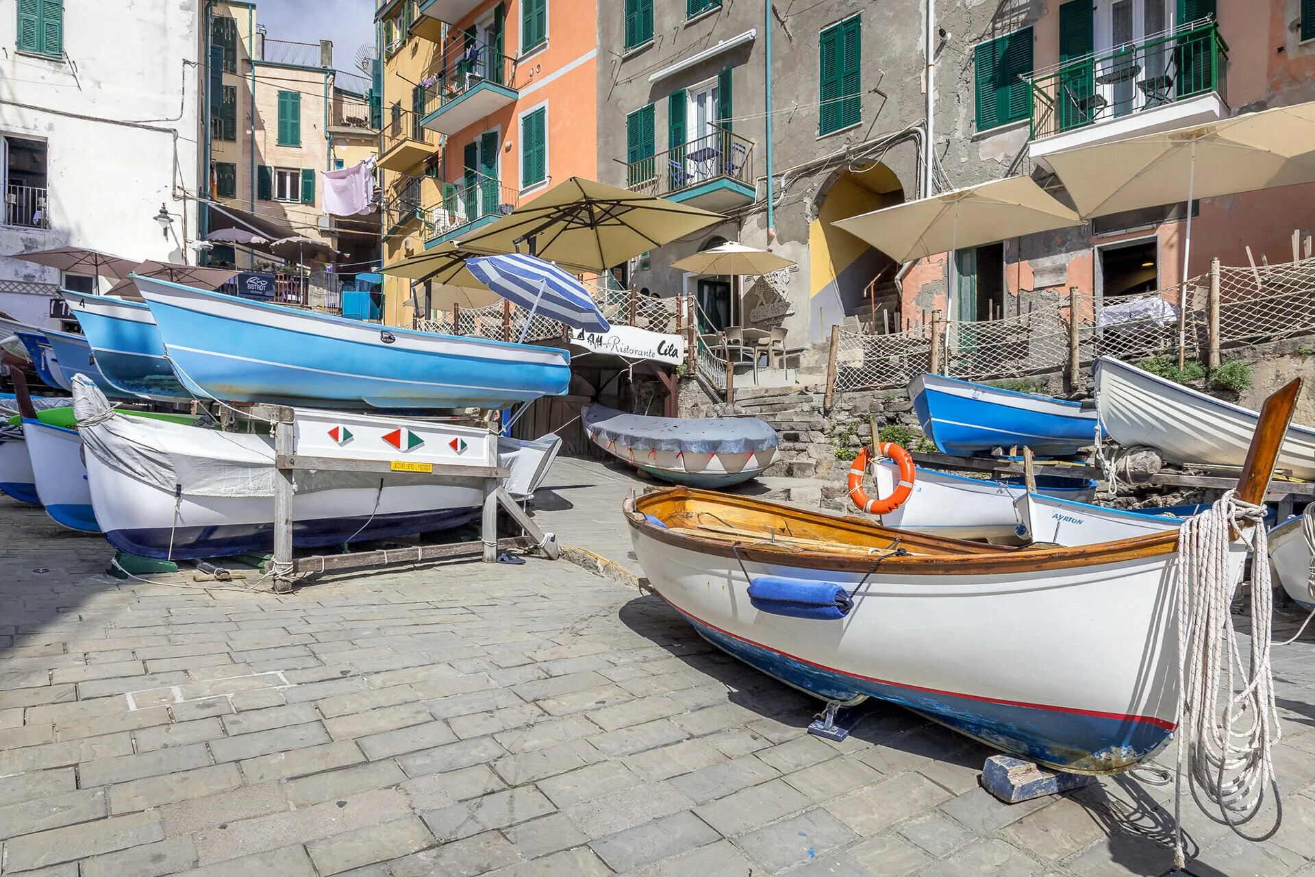 Colorful fishing boats rest in the harbor of Riomaggiore, one of the five picturesque villages of Cinque Terre, Italy.