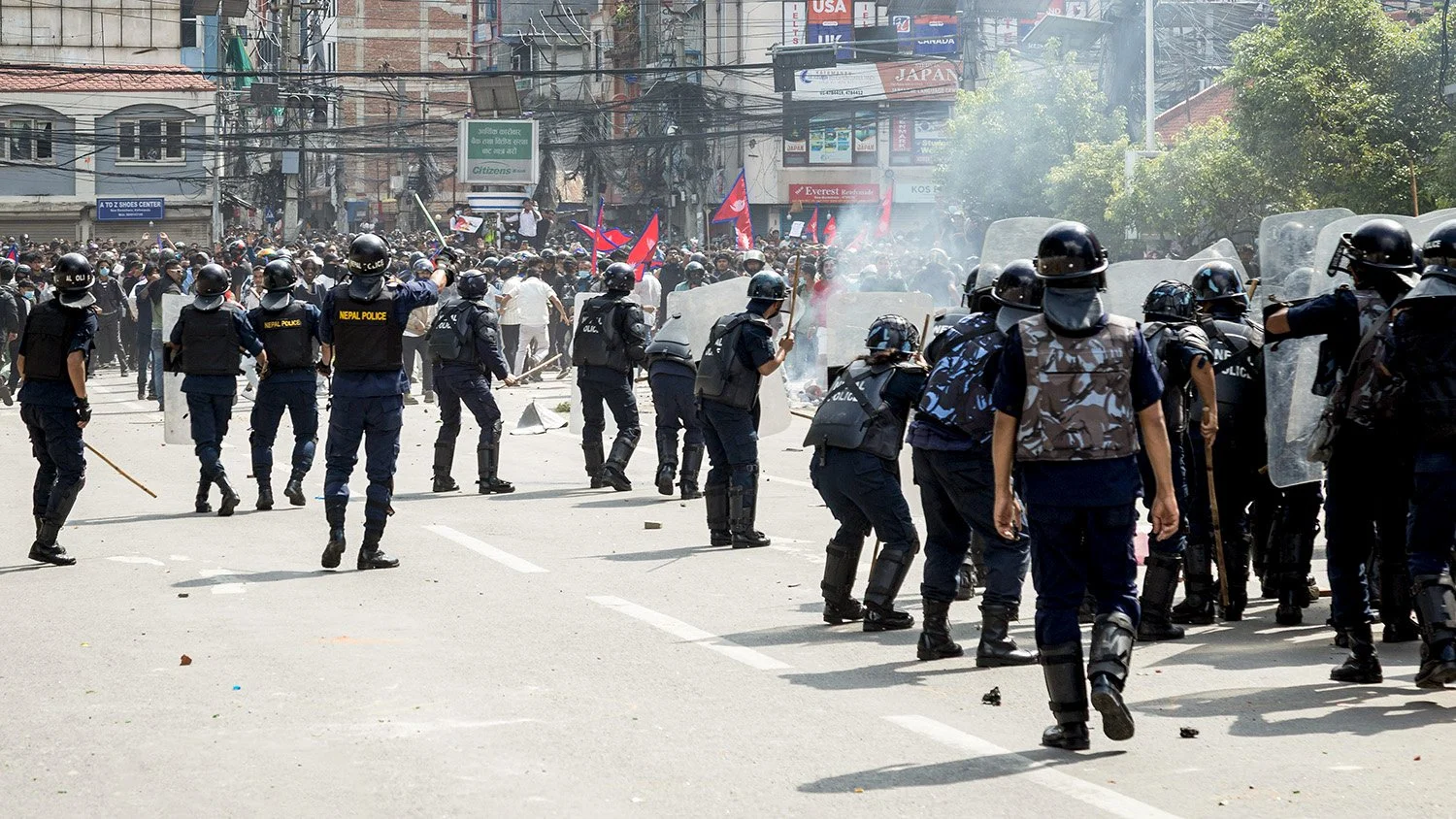 A police officer signals the charge as officers on the right fire toward protesters.