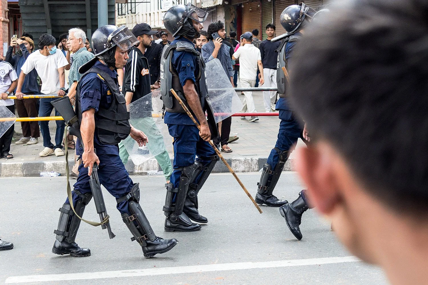  A police officer whistles while advancing, rifle in hand.