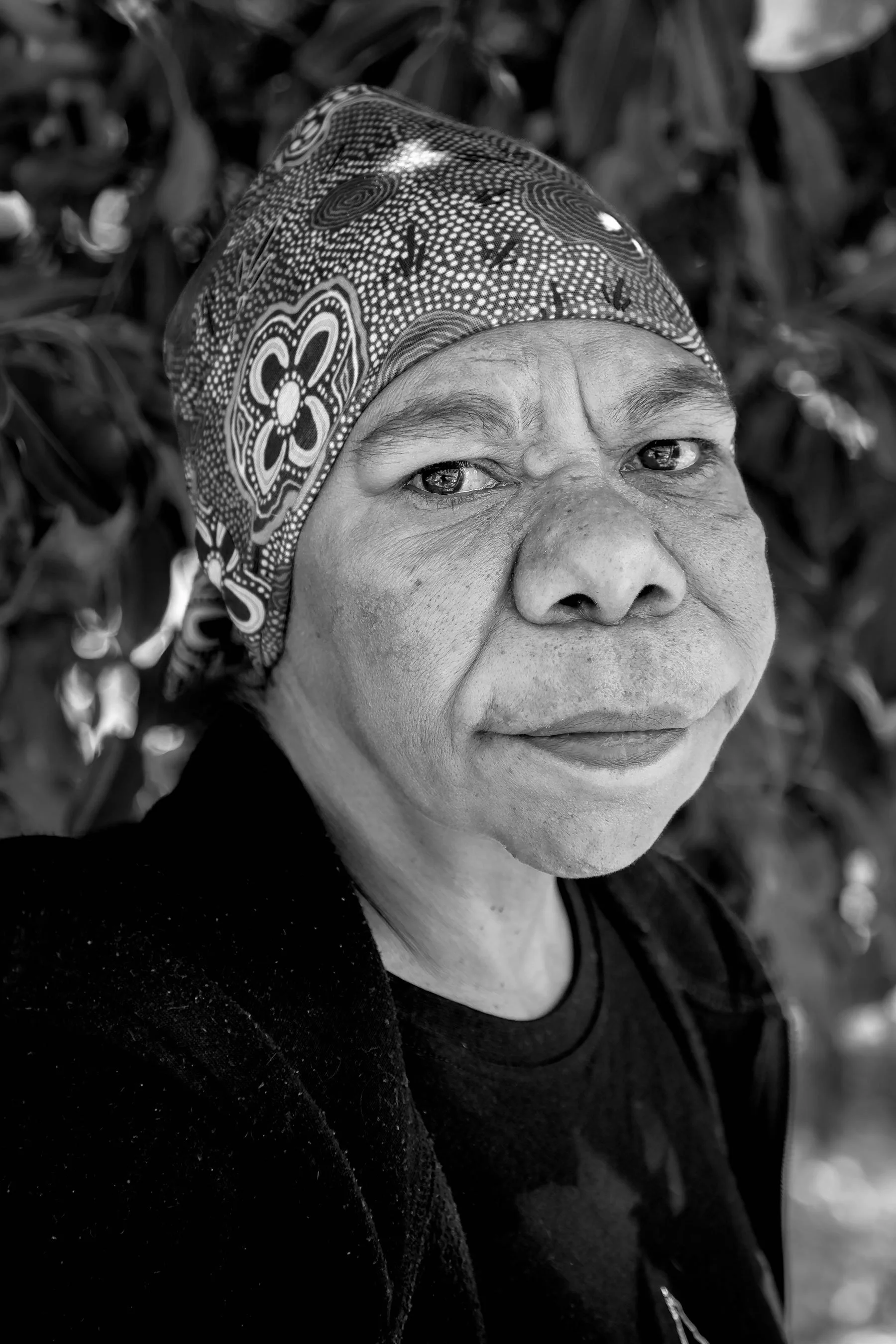 Portrait of artist Adrienne captured in stark black and white, the monochromatic treatment serving as a visual commentary on the marginalization of Aboriginal people in Australia.