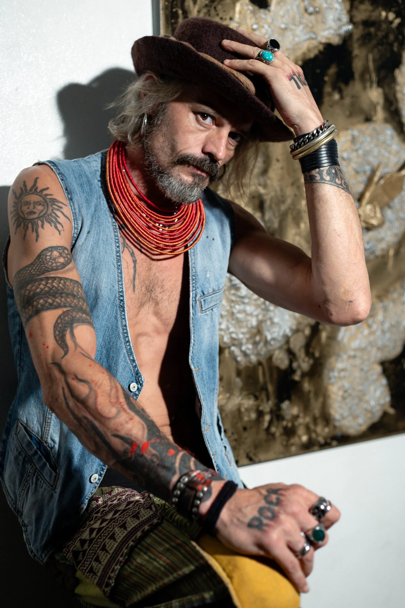 Artist Jerome Giustini works in his studio, his signature hat adding character to this intimate portrait captured amid his creative environment and artistic works.