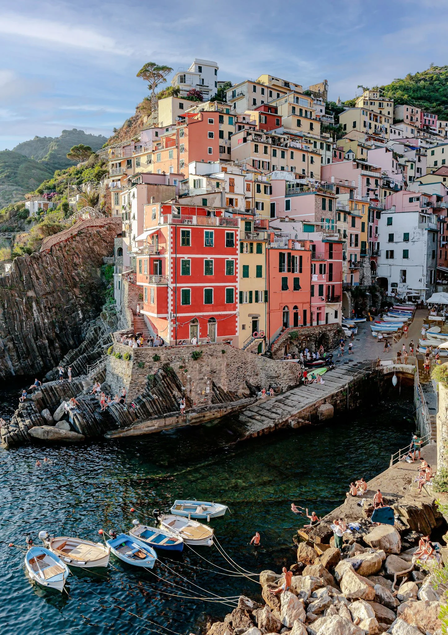 The picturesque village of Riomaggiore bathes in golden sunset light, its colorful houses cascading down the cliffside to meet the Ligurian Sea.