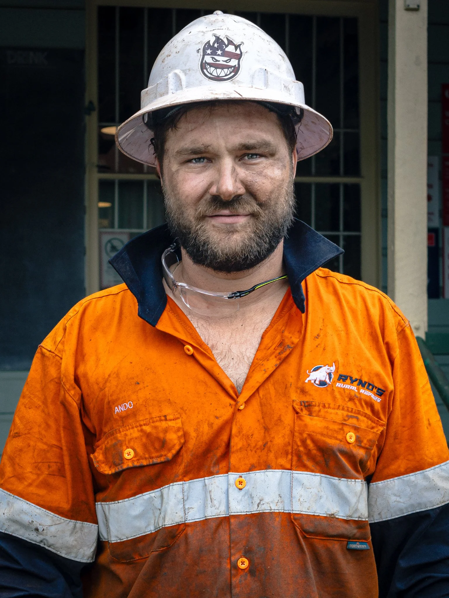 Factory worker Dano takes his lunch break, his face and work clothes still bearing the marks of grease and labor from the industrial floor.
