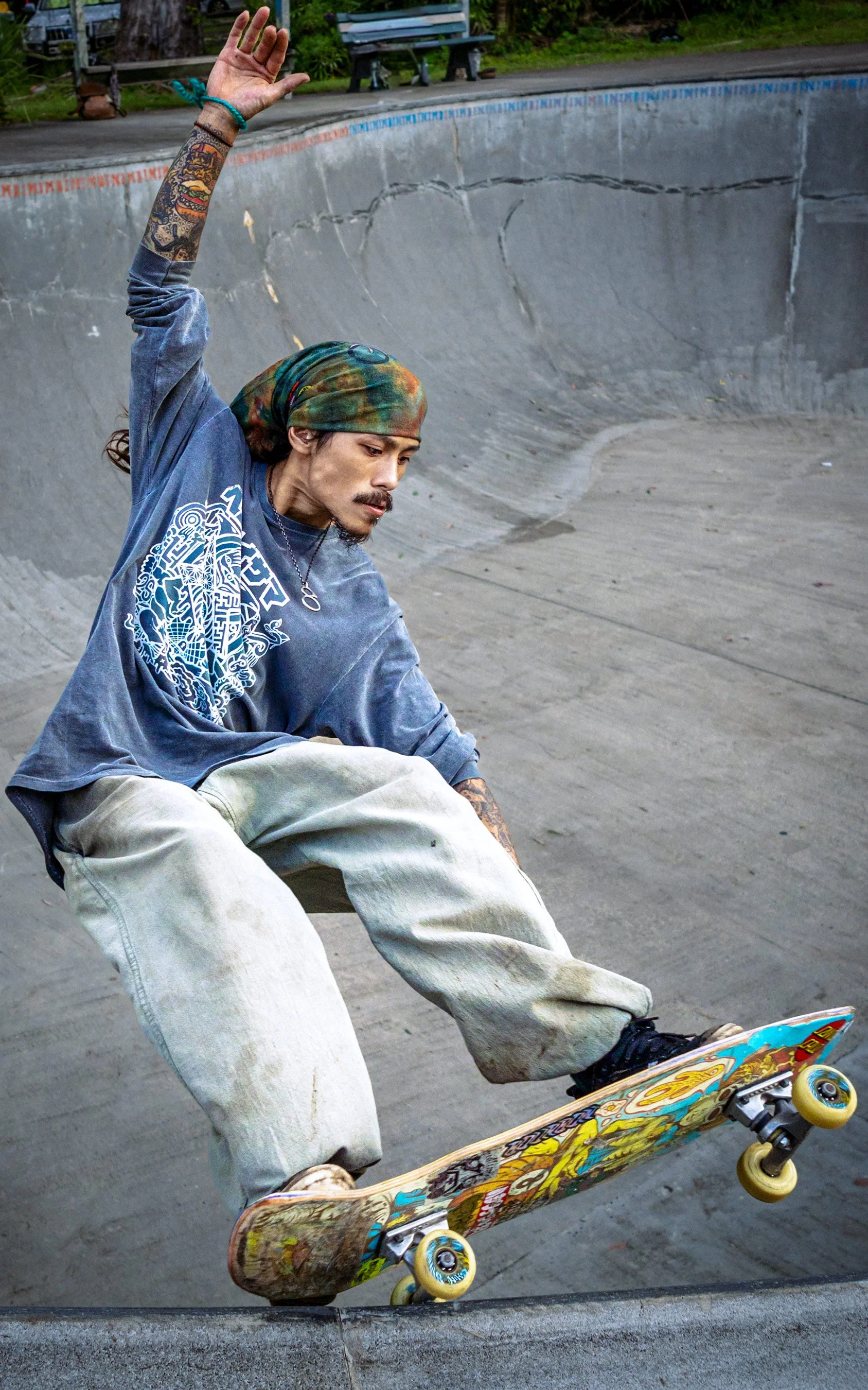 Skater Rikya executes a trick at Nimbin Skate Park, captured mid-motion as he demonstrates his skill and style on the concrete features.