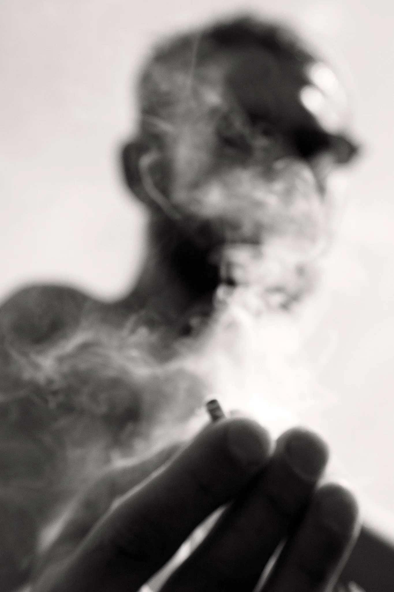 A stranger extends a joint through a veil of smoke, their face obscured in the hazy moment of shared connection on the street.