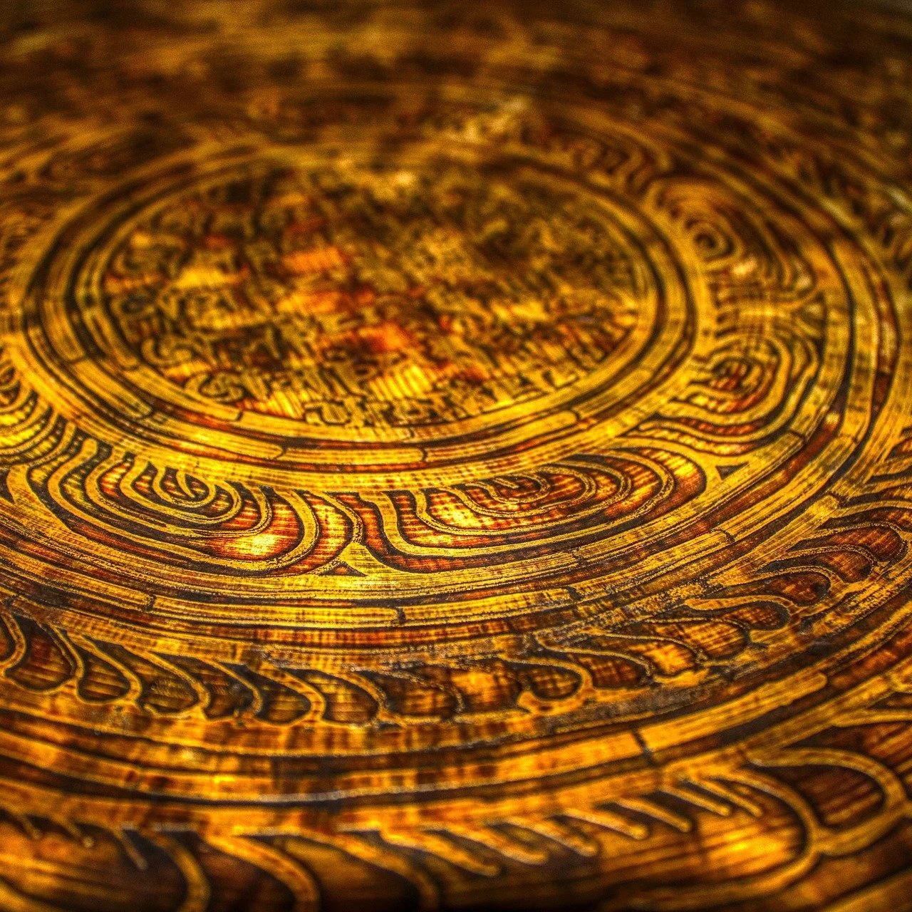 Close-up of an ancient gold coin with intricate circular engravings and patterns.
