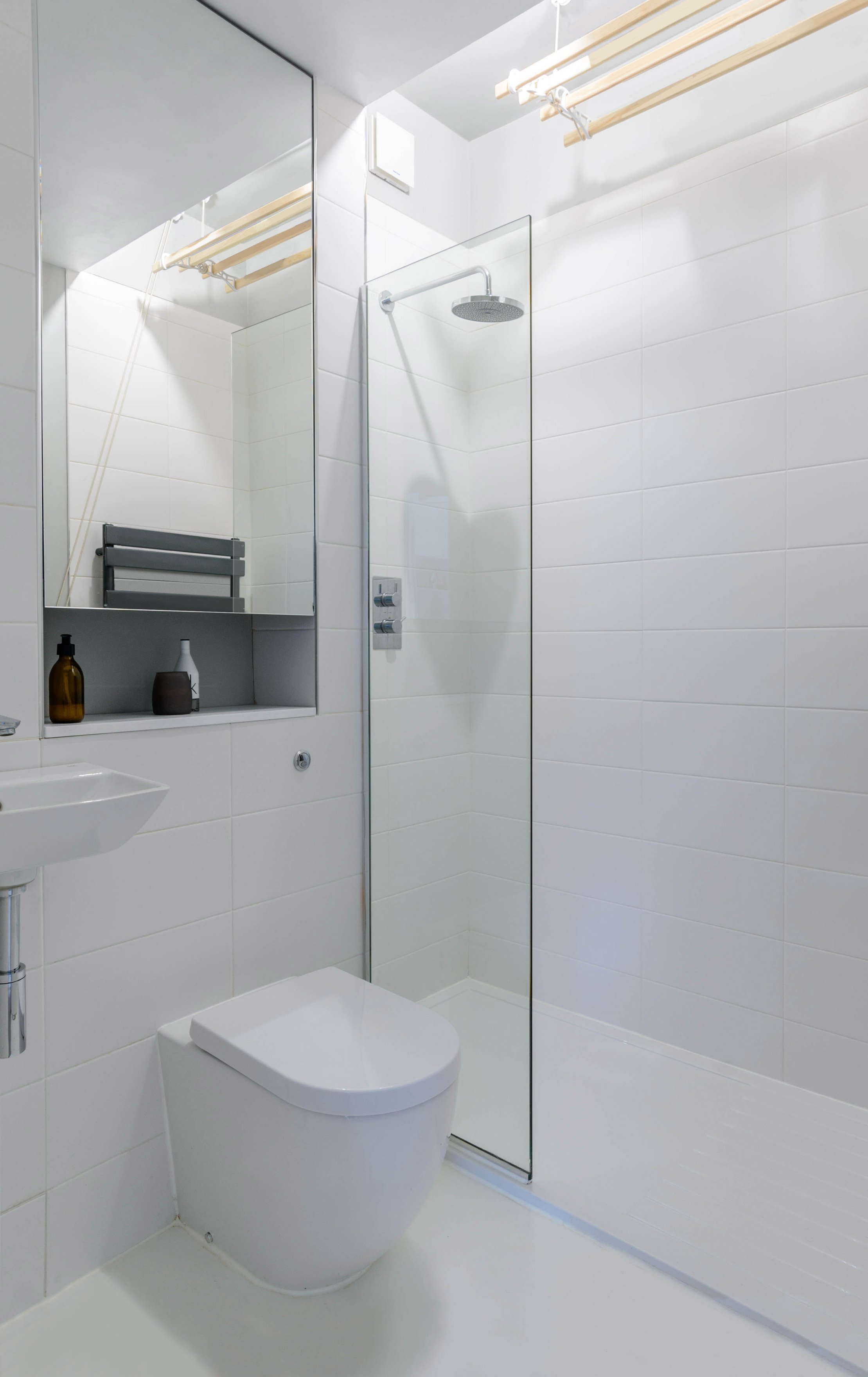 Modern interior architecture of a bathroom space with plain white floor and white tiled walls.