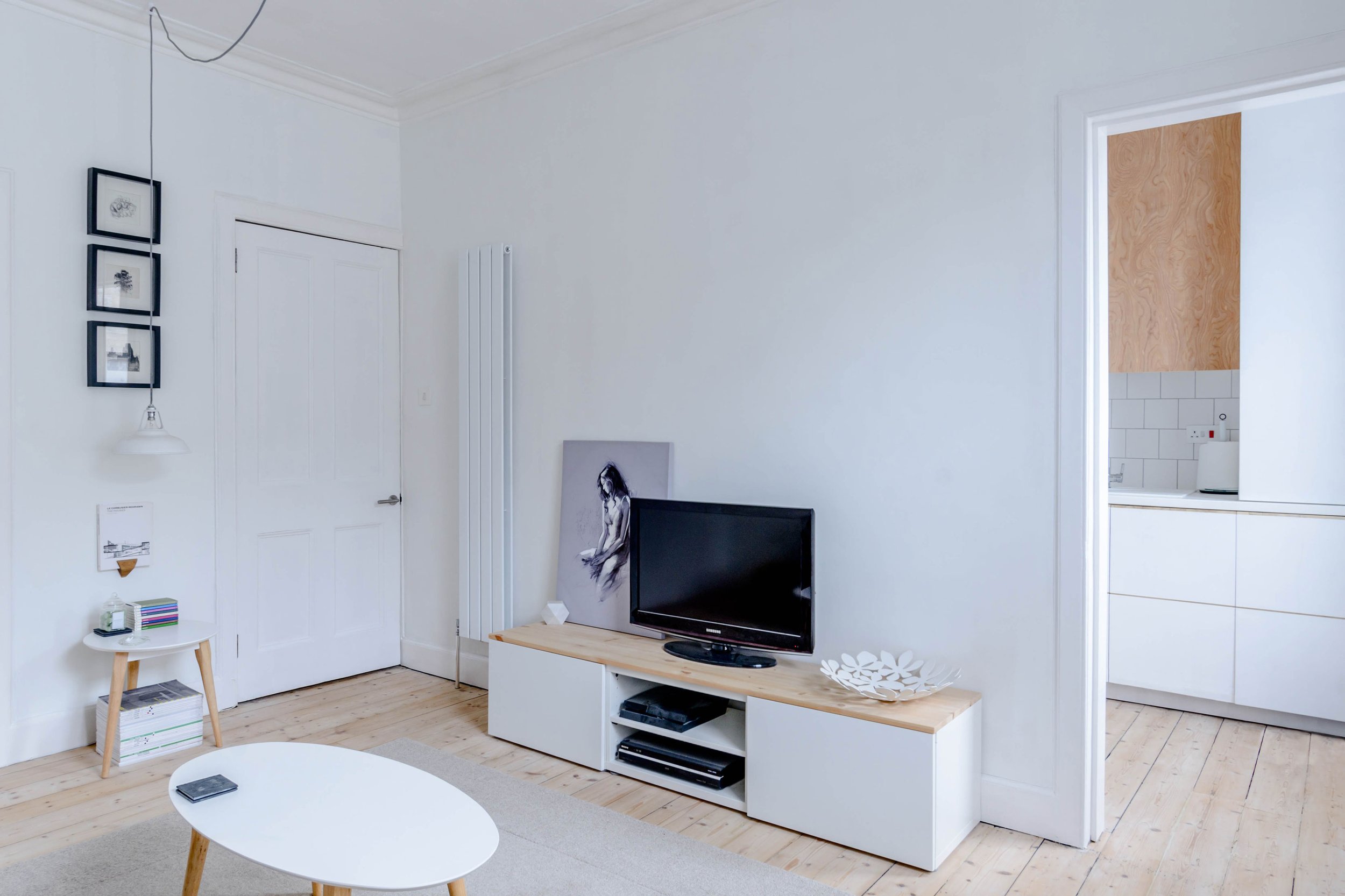 Modern interior architecture of a lounge space showing a TV with wooden floor and white walls.