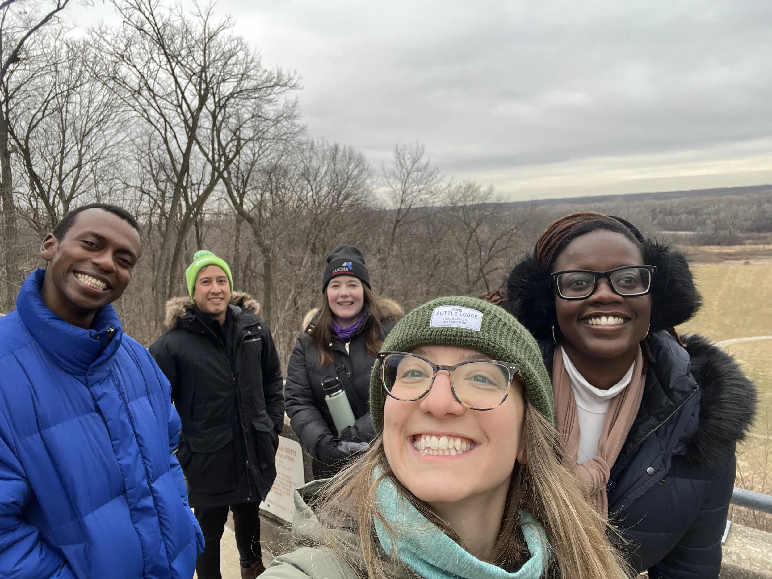Five people pose for a selfie while hiking in the winter