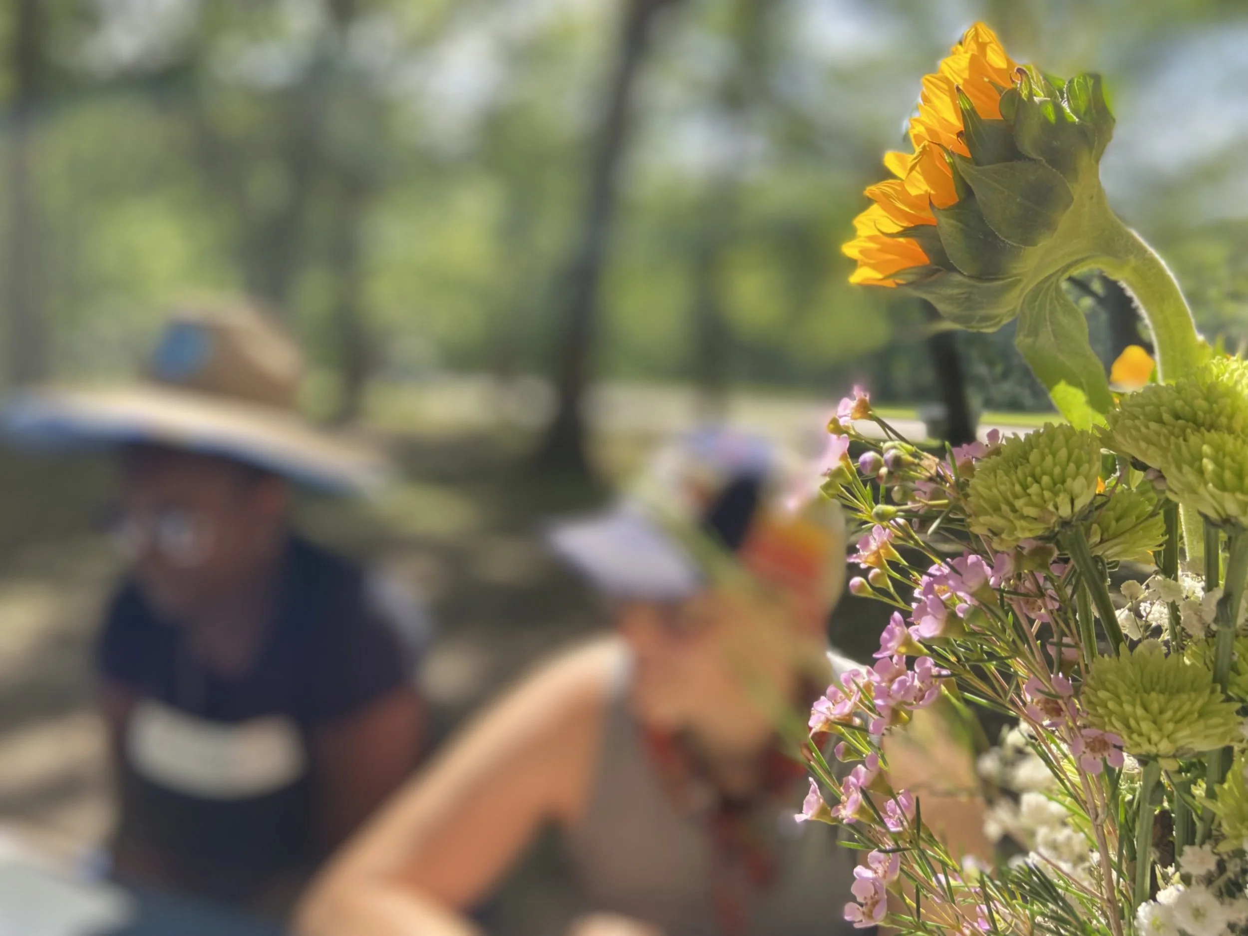 Two people sit and conversation with a bouquet of flowers in the foreground