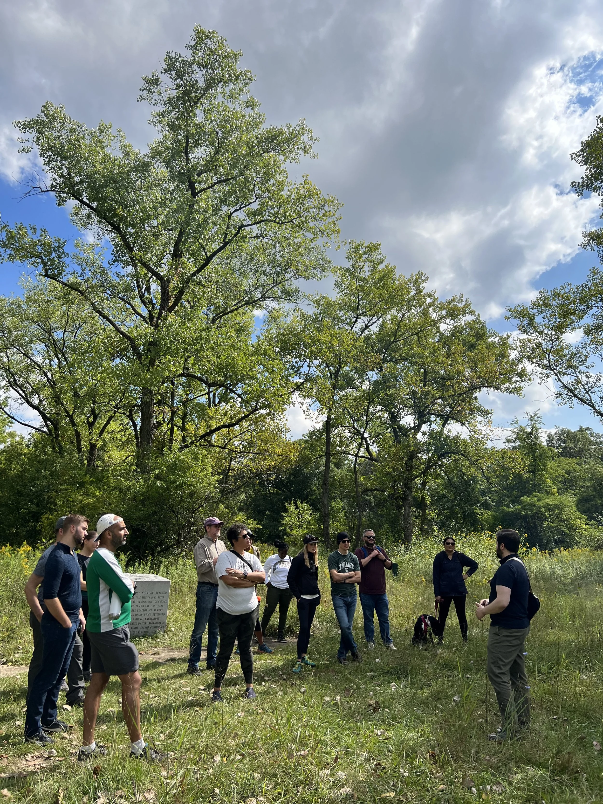 group of people standing around each other in a green forest
