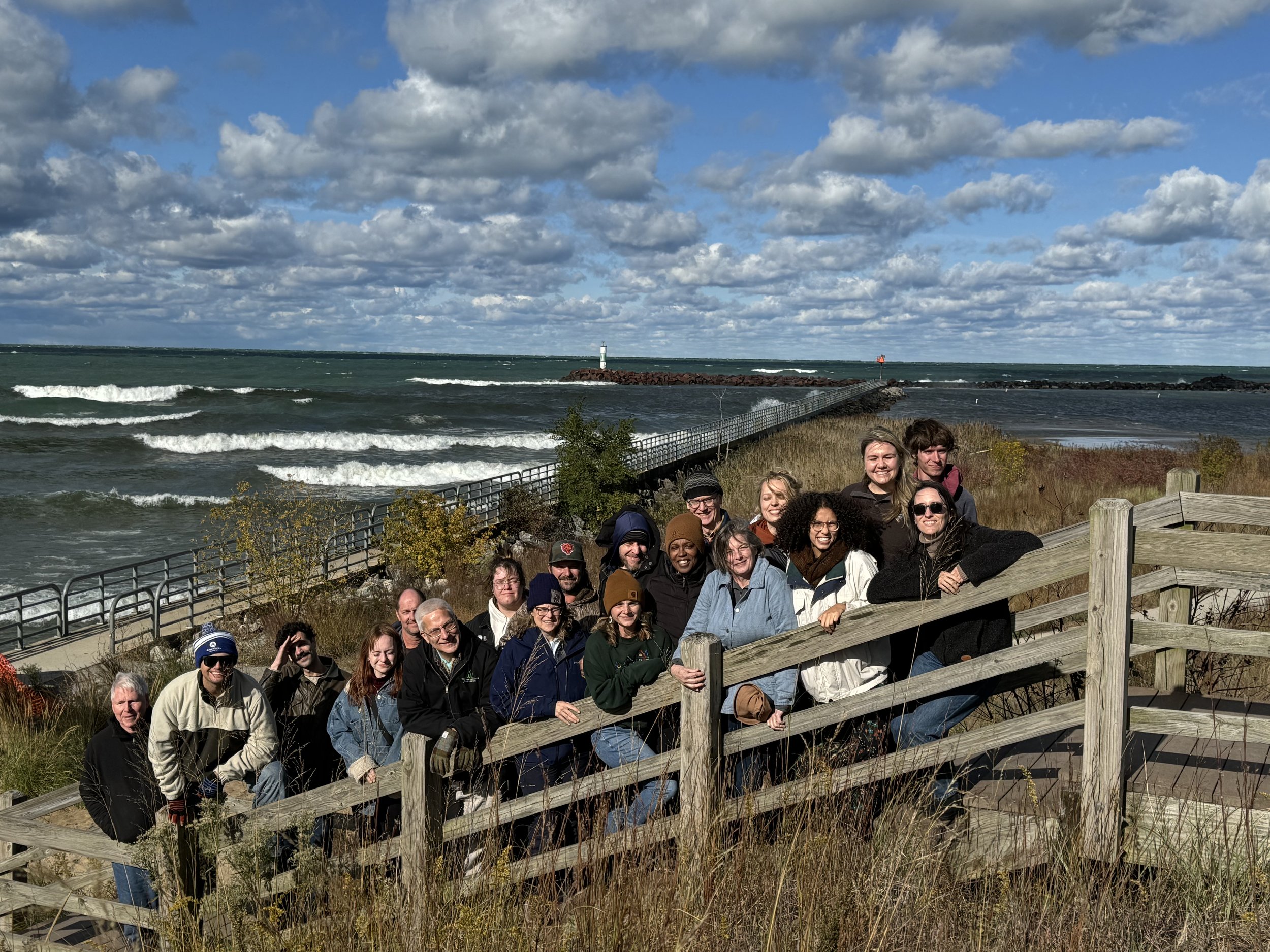 The staff of the Wetlands Initiative stands on a wooden staircase with Lake Michigan in the background