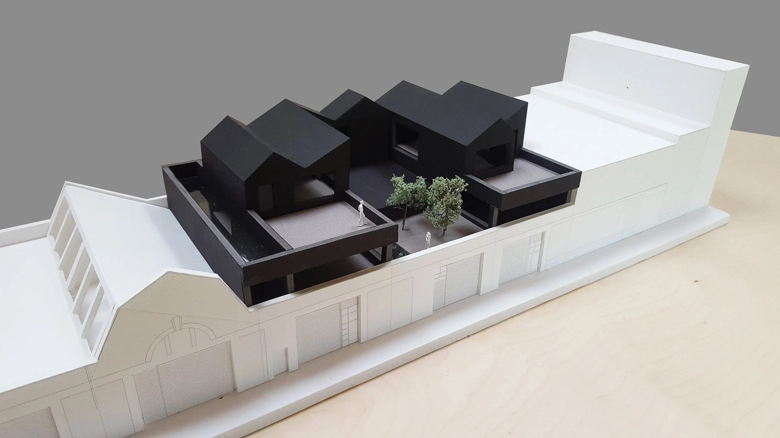 Architectural model of a modern building with black and white sections, trees, and miniature figures, on a white base.
