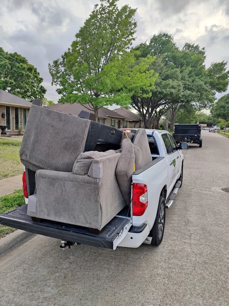 Furniture removal in Plano, TX with a large sofa loaded onto a pickup truck for hauling.