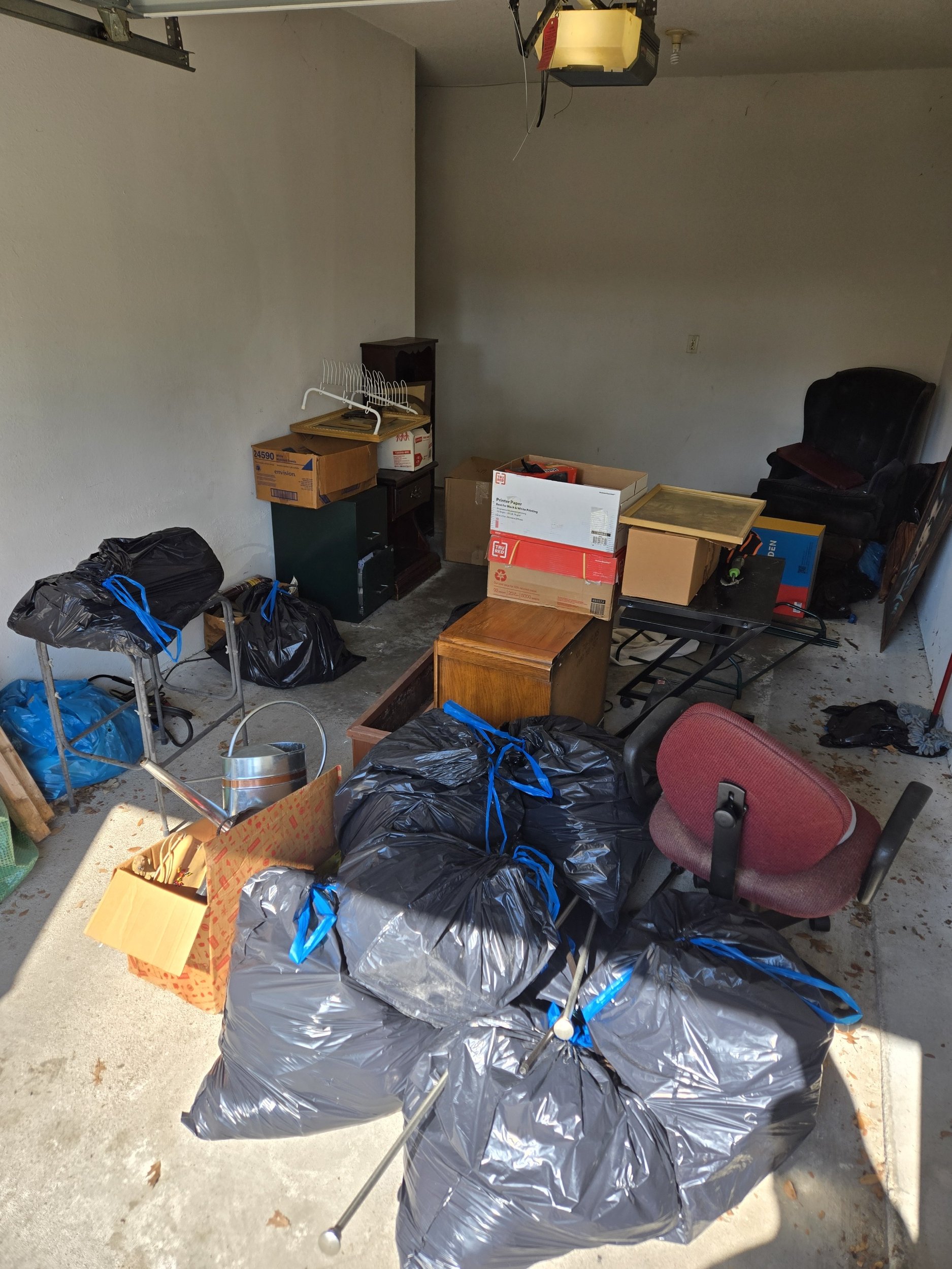Garage before junk removal and cleanout service in Richardson, TX with unwanted furniture, bags, boxes, and household items.