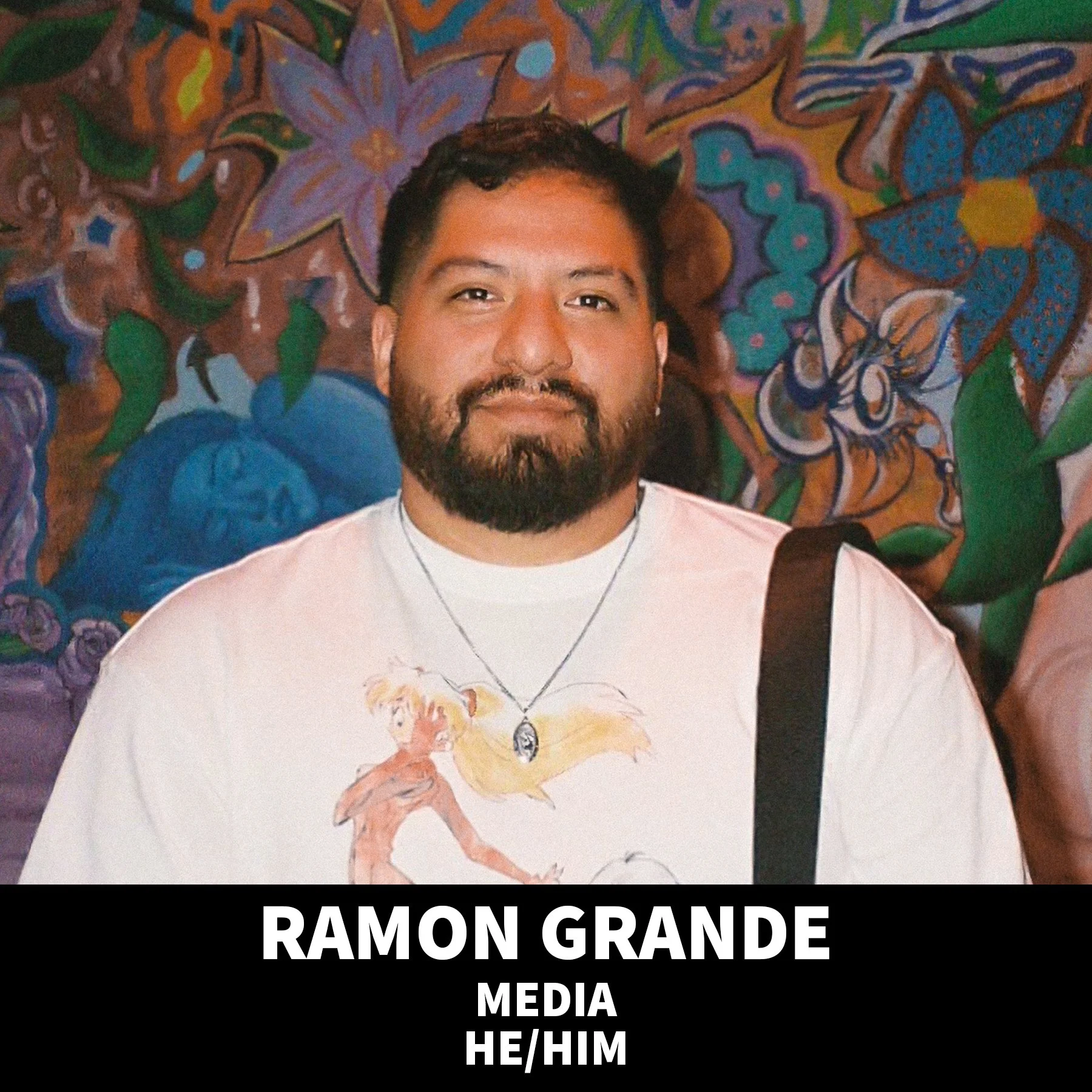 Smiling man wearing a black beanie and black T-shirt against a black background.