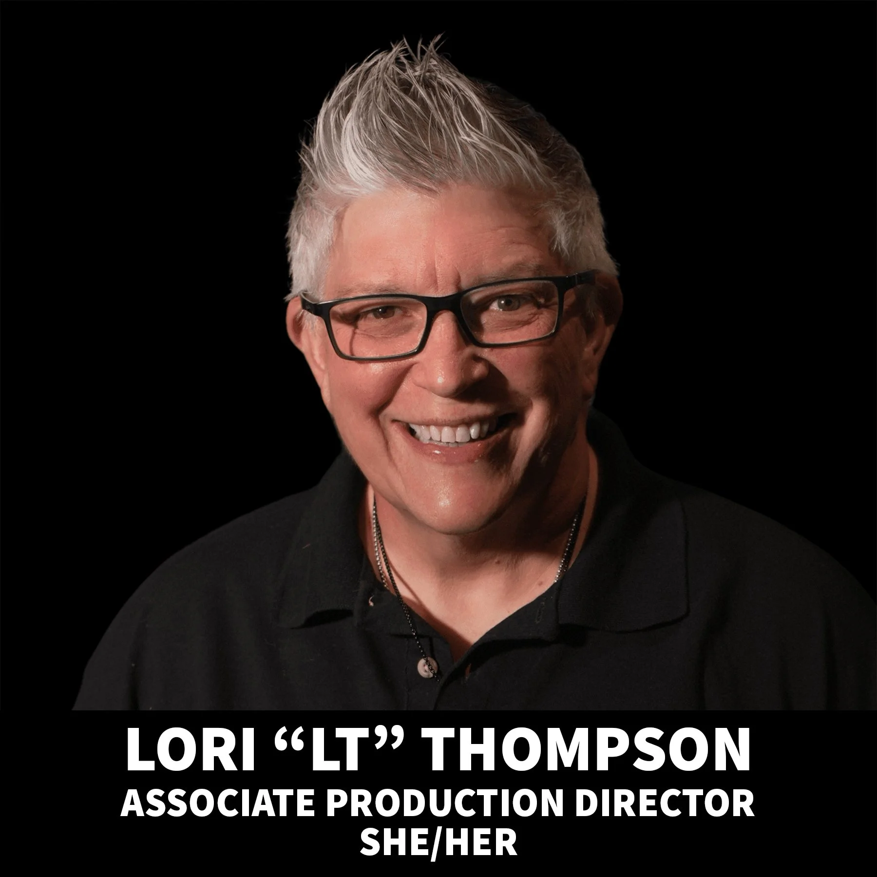 A smiling man with gray hair, glasses, wearing a black polo shirt with a logo, against a black background.