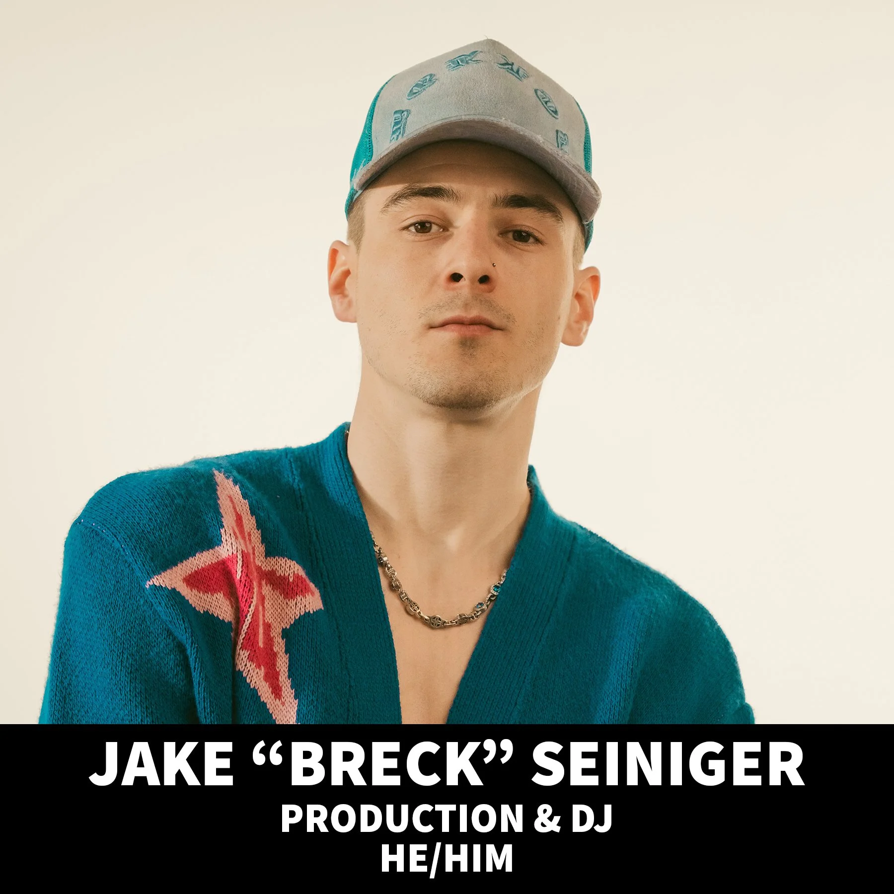 Portrait of a young man with short hair, wearing a black shirt, standing against a black background.