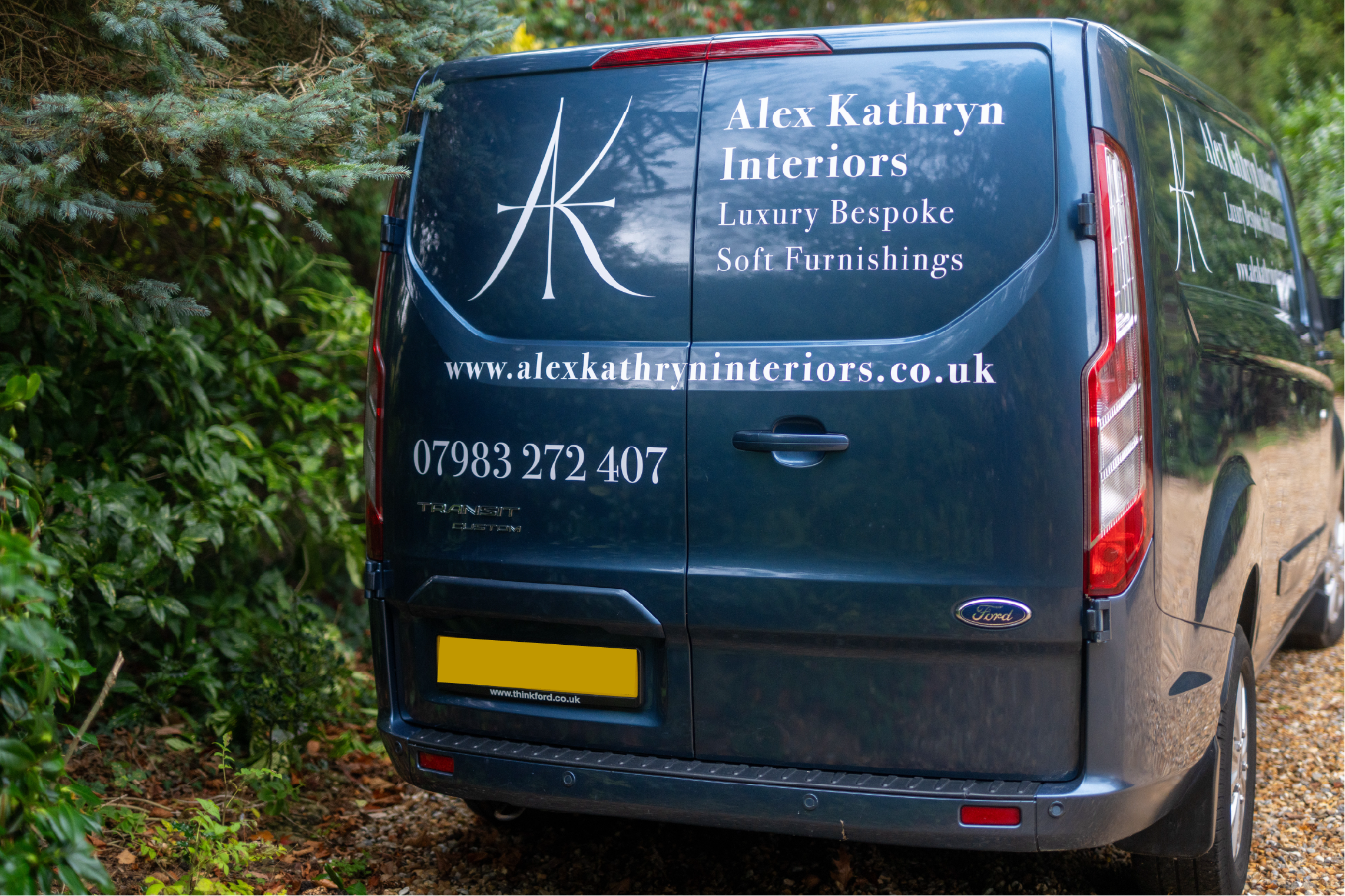 A dark blue van with branding advertising Alex Kathryn Interiors, a luxury bespoke soft furnishings business. The van features a large logo with the initials 'AK' and the website www.alexkathryninteriors.co.uk along with contact details.