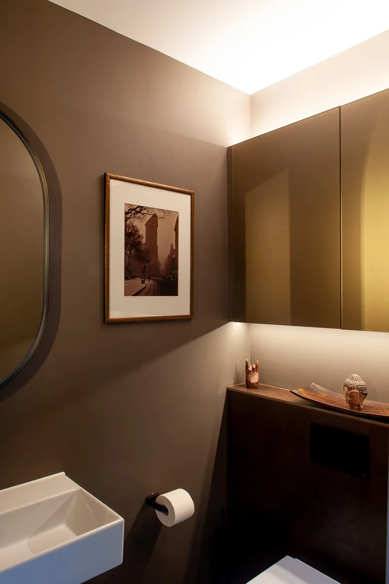 Compact refurbished WC with fitted vanity storage, mirror and warm concealed lighting
