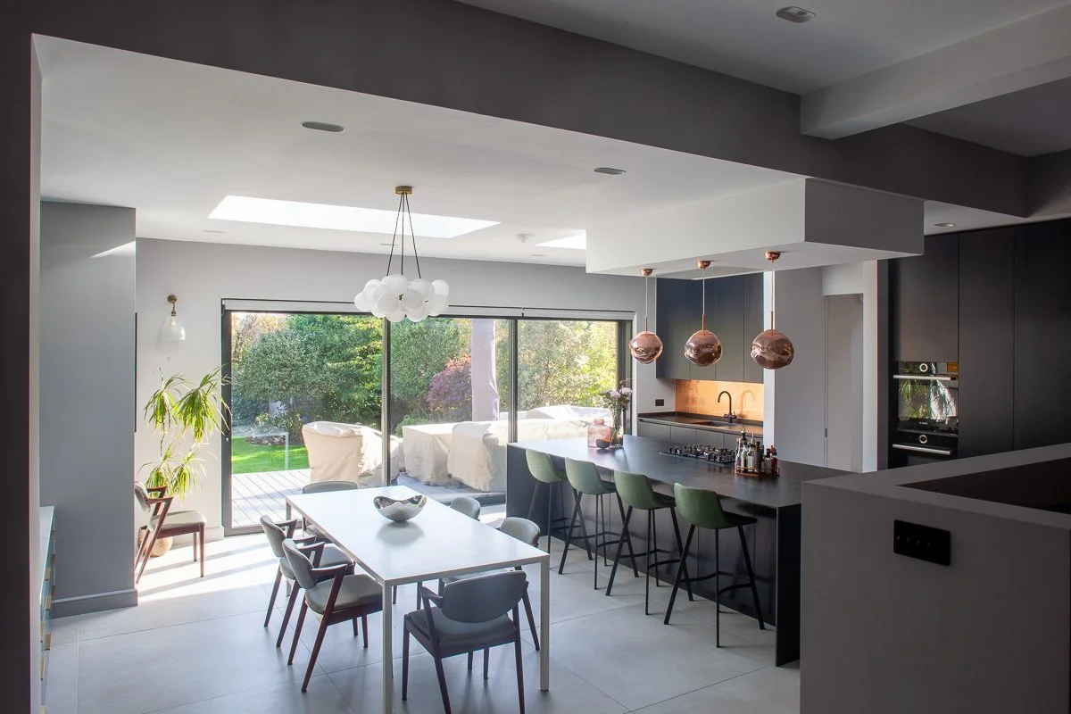 Completed open-plan London kitchen with dark cabinetry, central island, rooflights and garden access