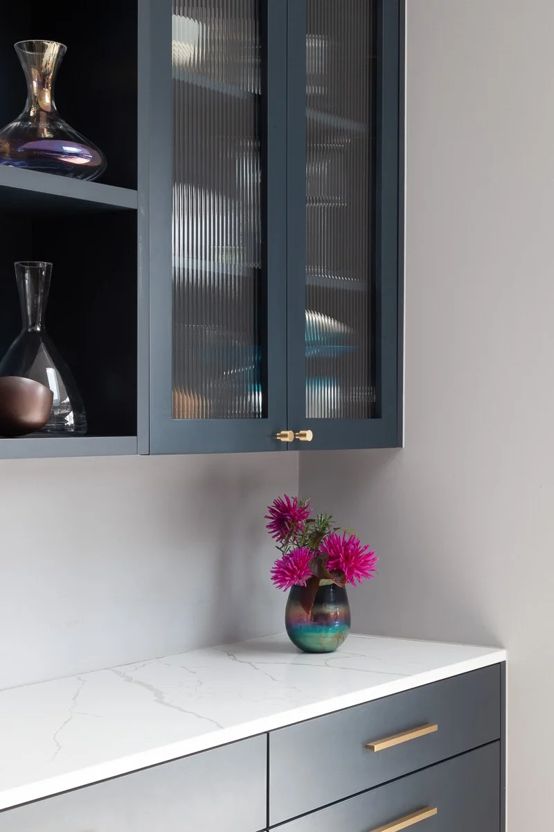 Bespoke dark fitted cabinetry with fluted glazing and brass hardware