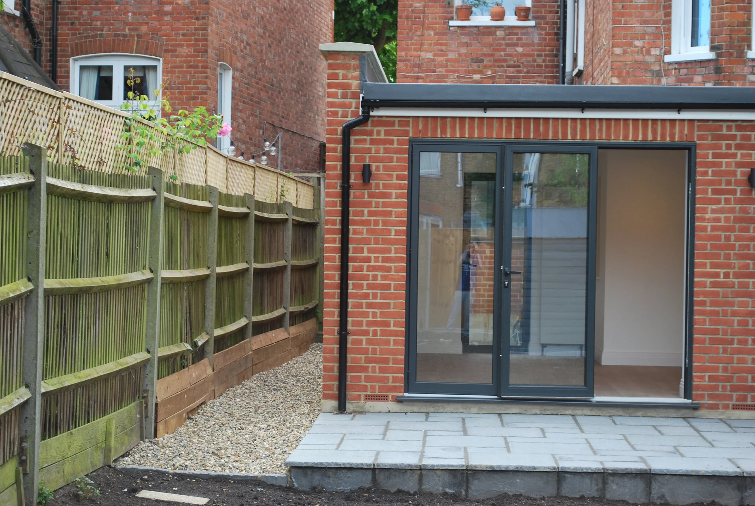 Completed rear extension to a London brick property with glazed doors and landscaped access