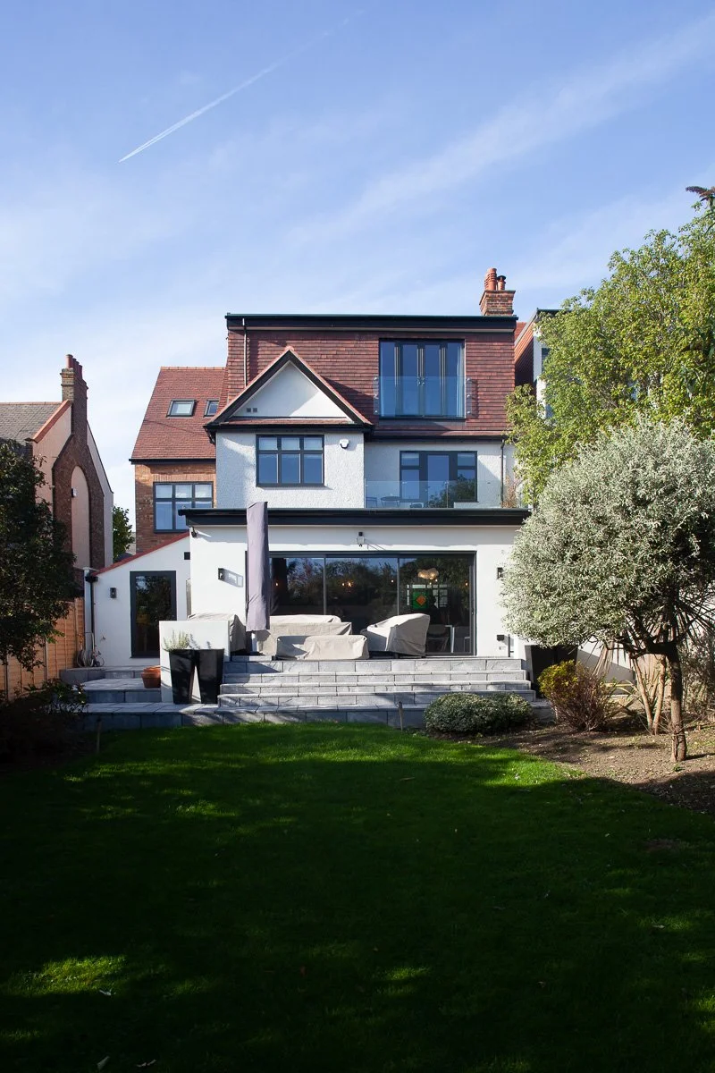 London house with completed rear extension and converted upper roof space viewed from the garden