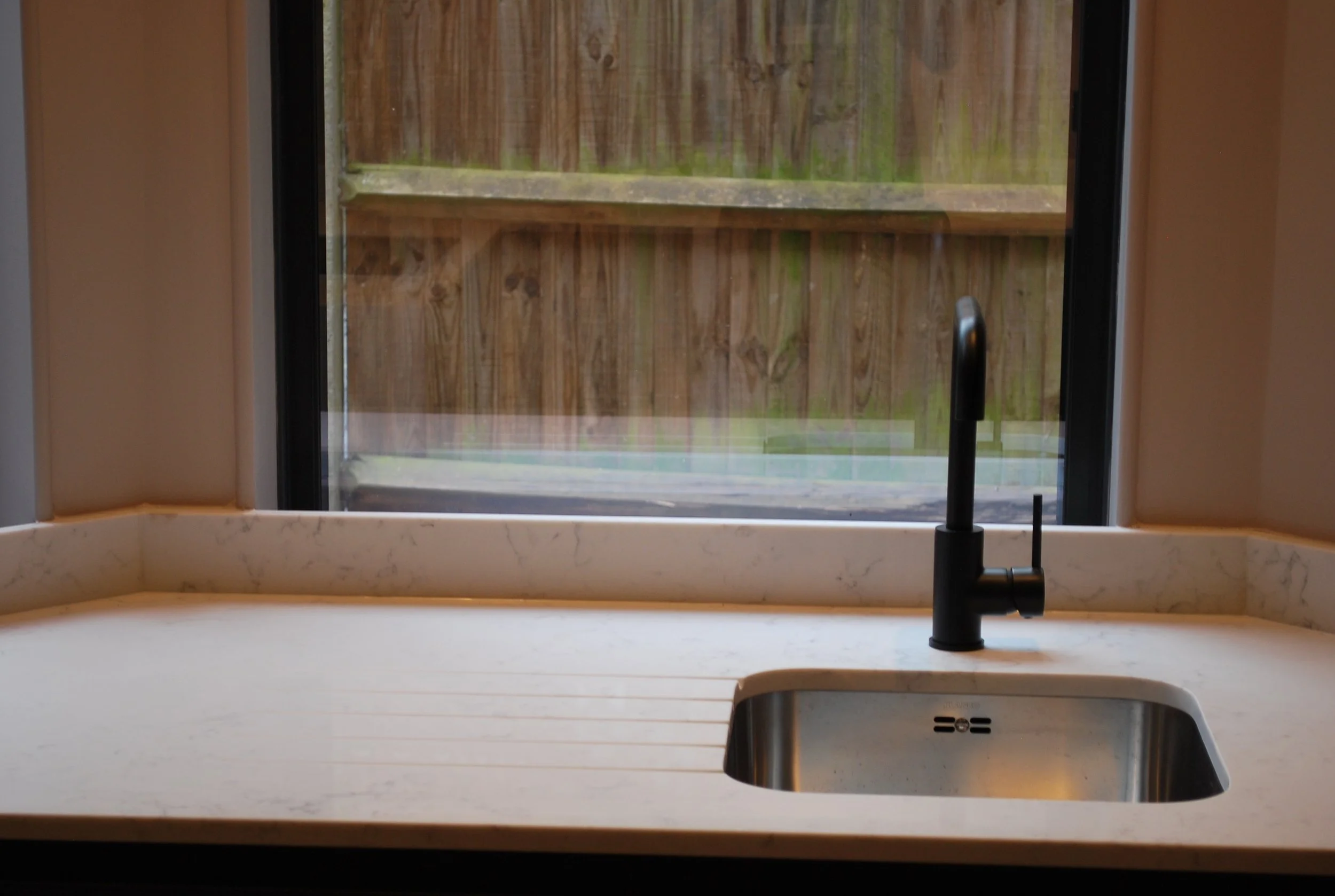 Black kitchen tap and undermounted sink installed in a stone worktop