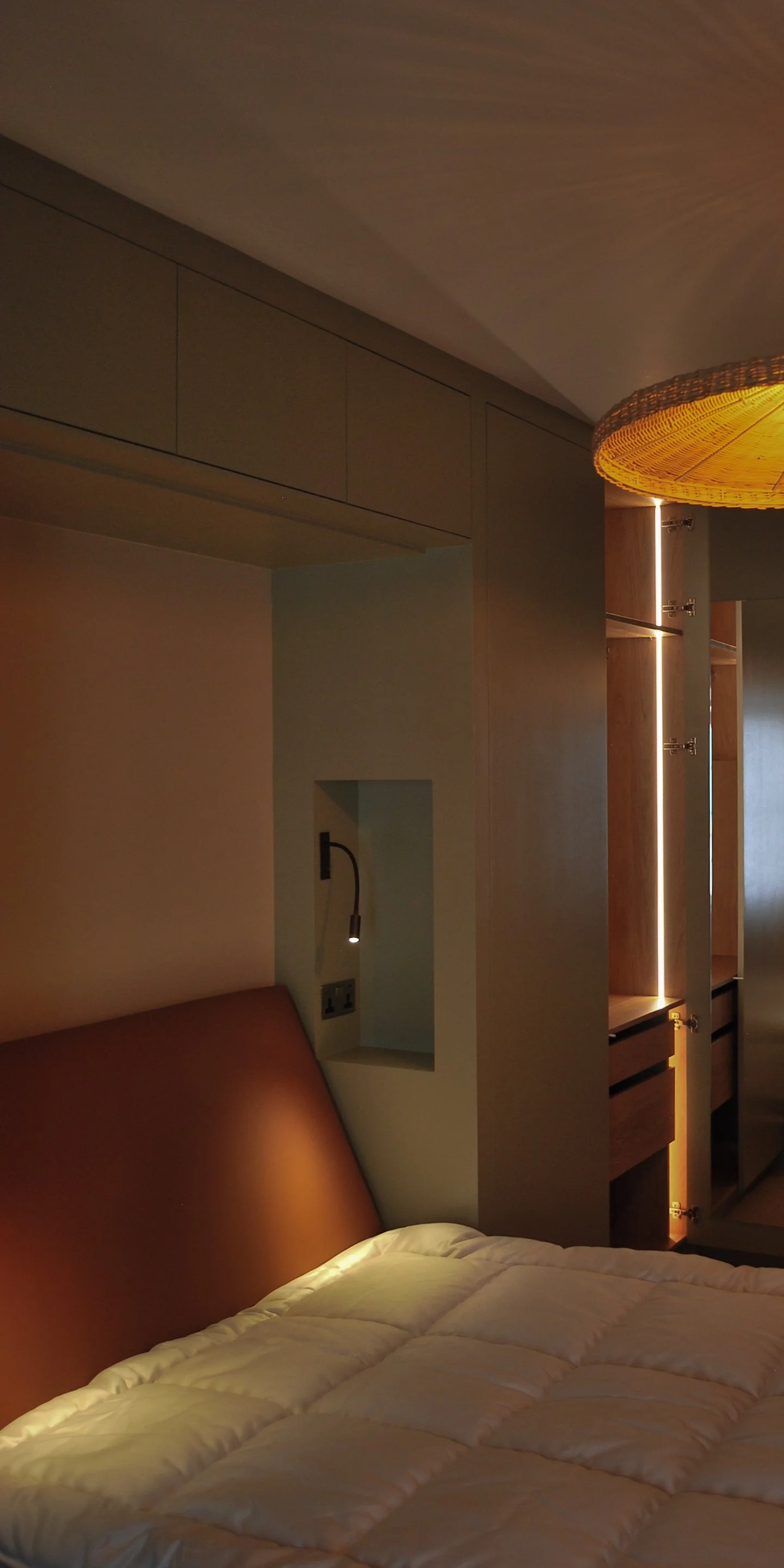 Bedside task lighting and electrical power coordinated with fitted bedroom furniture