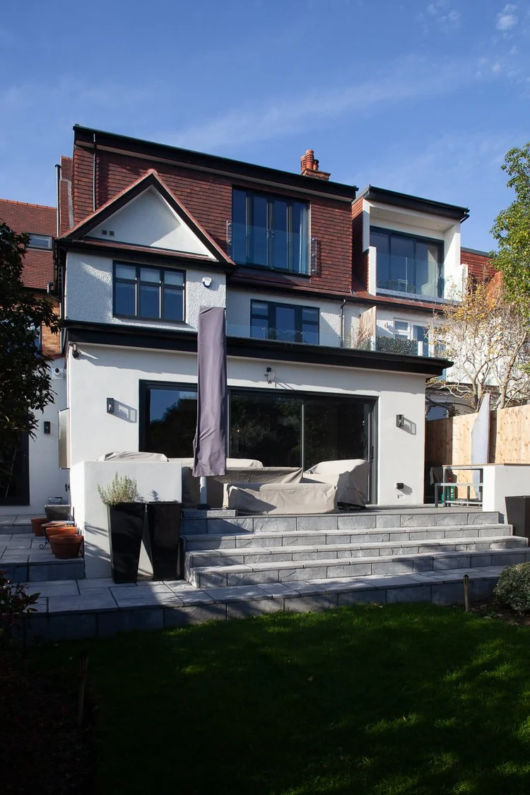 London rear garden with lawn, paved terrace and steps connecting the garden to the refurbished home