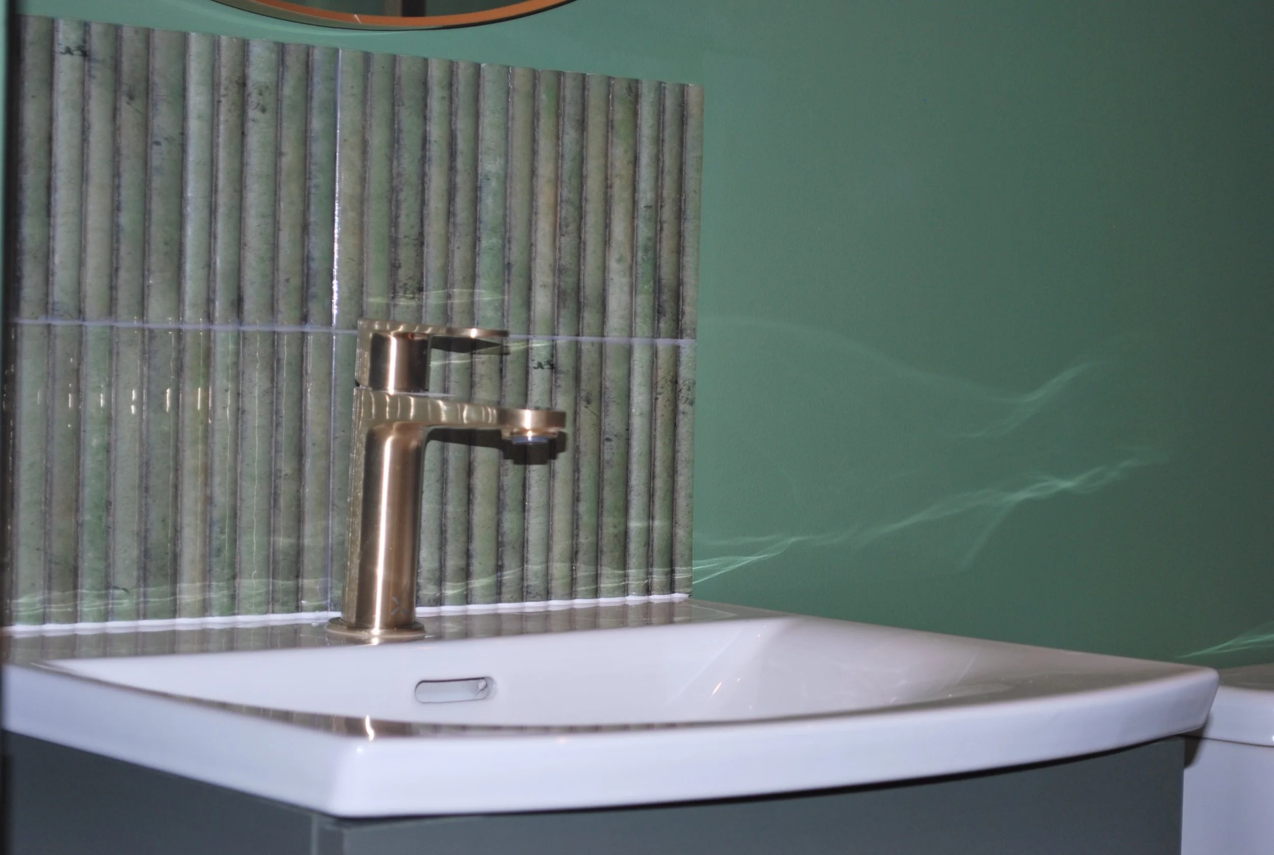 Bathroom basin and mixer tap set against fluted tile and a teal painted wall