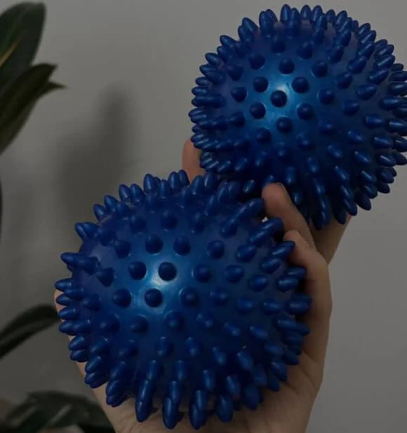 Person holding two blue spiky massage balls